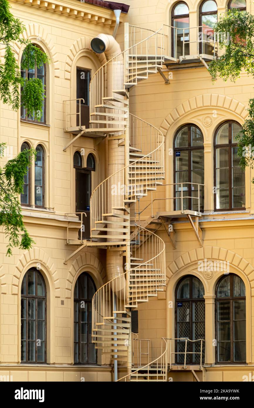 Nykoping, Suède - 13 juin, 2022: Détails architecturaux en gros plan de l'escalier métallique en spirale menant vers le bas du mur extérieur de jaune rendent traditionnel 1 Banque D'Images