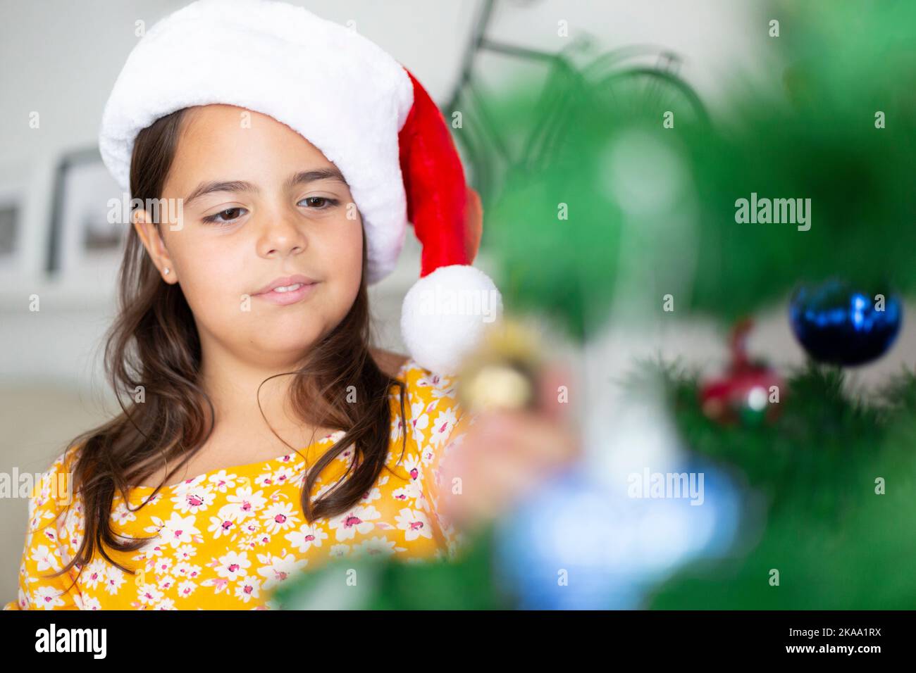 Gros plan d'un petit enfant décorant un arbre de Noël à la maison. Espace pour le texte. Banque D'Images