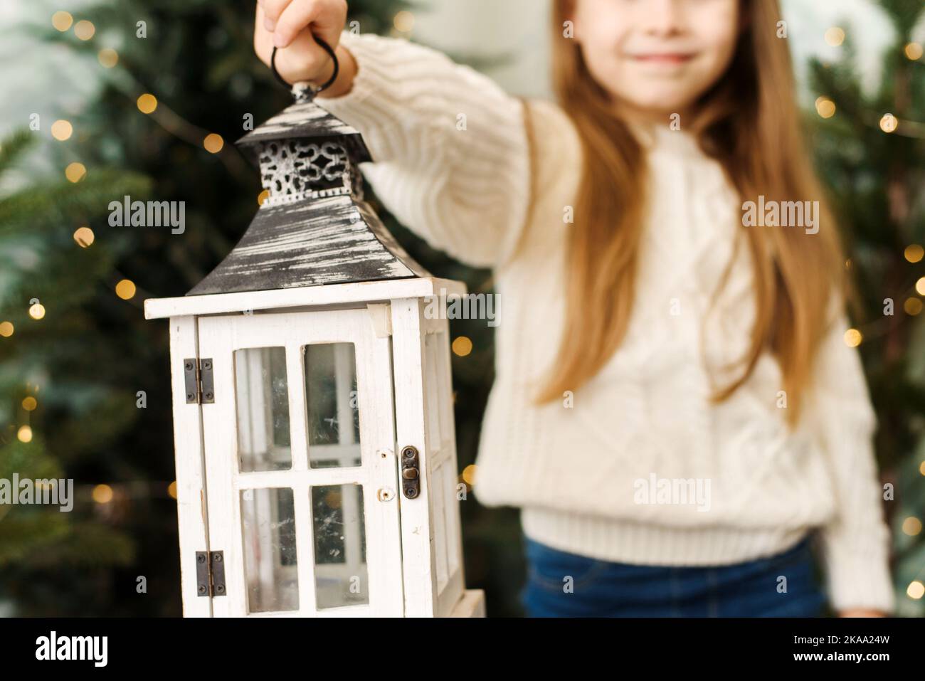 Jolie petite fille tenant une lanterne de Noël parmi les arbres de Noël Banque D'Images