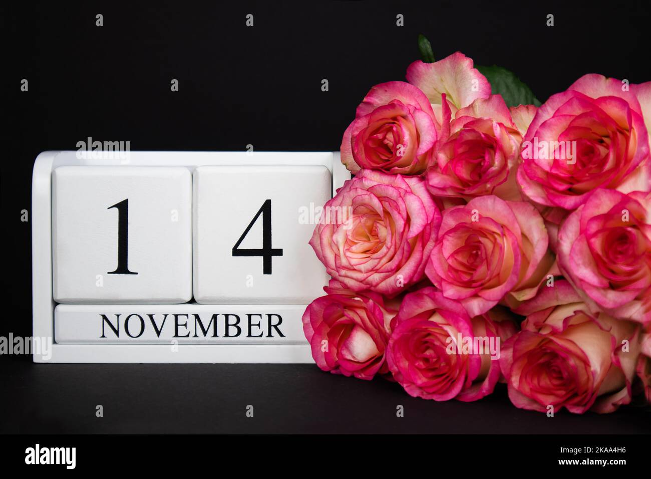 14 novembre calendrier en bois, blanc sur fond noir, roses se trouvent à proximité. Banque D'Images