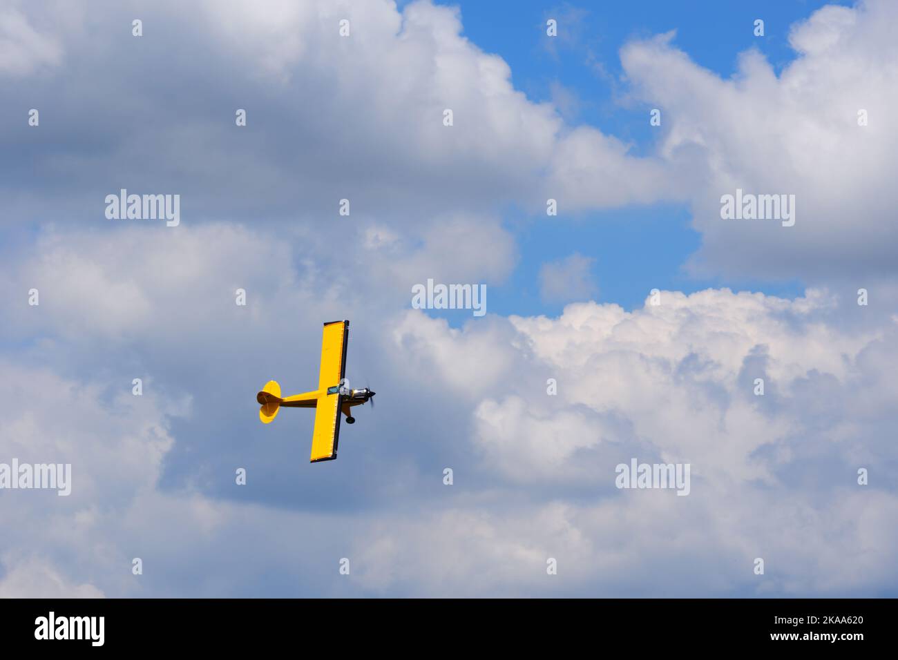 Petit avion jaune au ciel, ayant tourne au ciel bleu avec des nuages clairs Banque D'Images