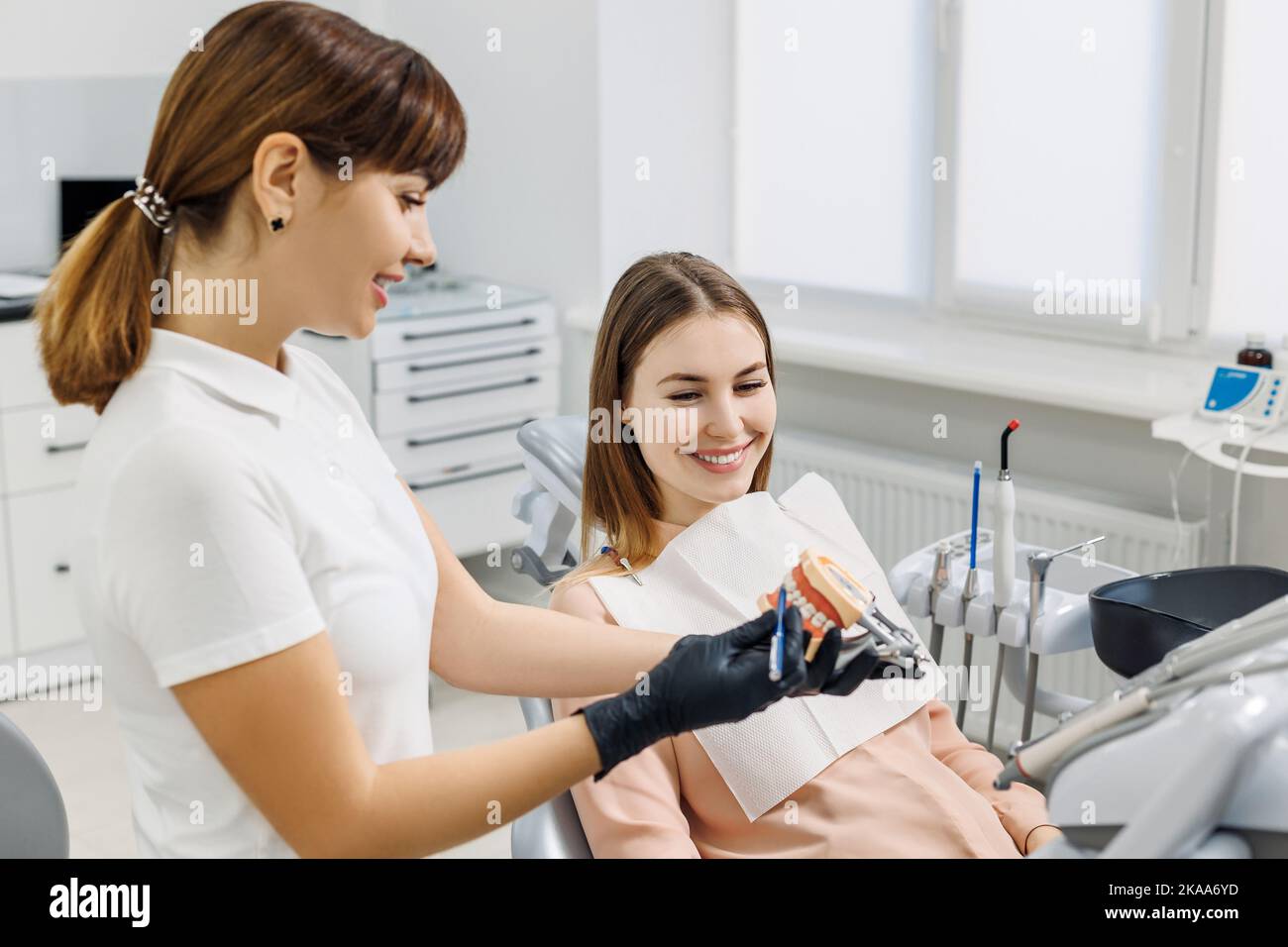 Un dentiste souriant démontrera une maquette de la mâchoire humaine et explique la prévention et le traitement des caries. Modèle de dents dans les mains du médecin. Photo de concept Banque D'Images