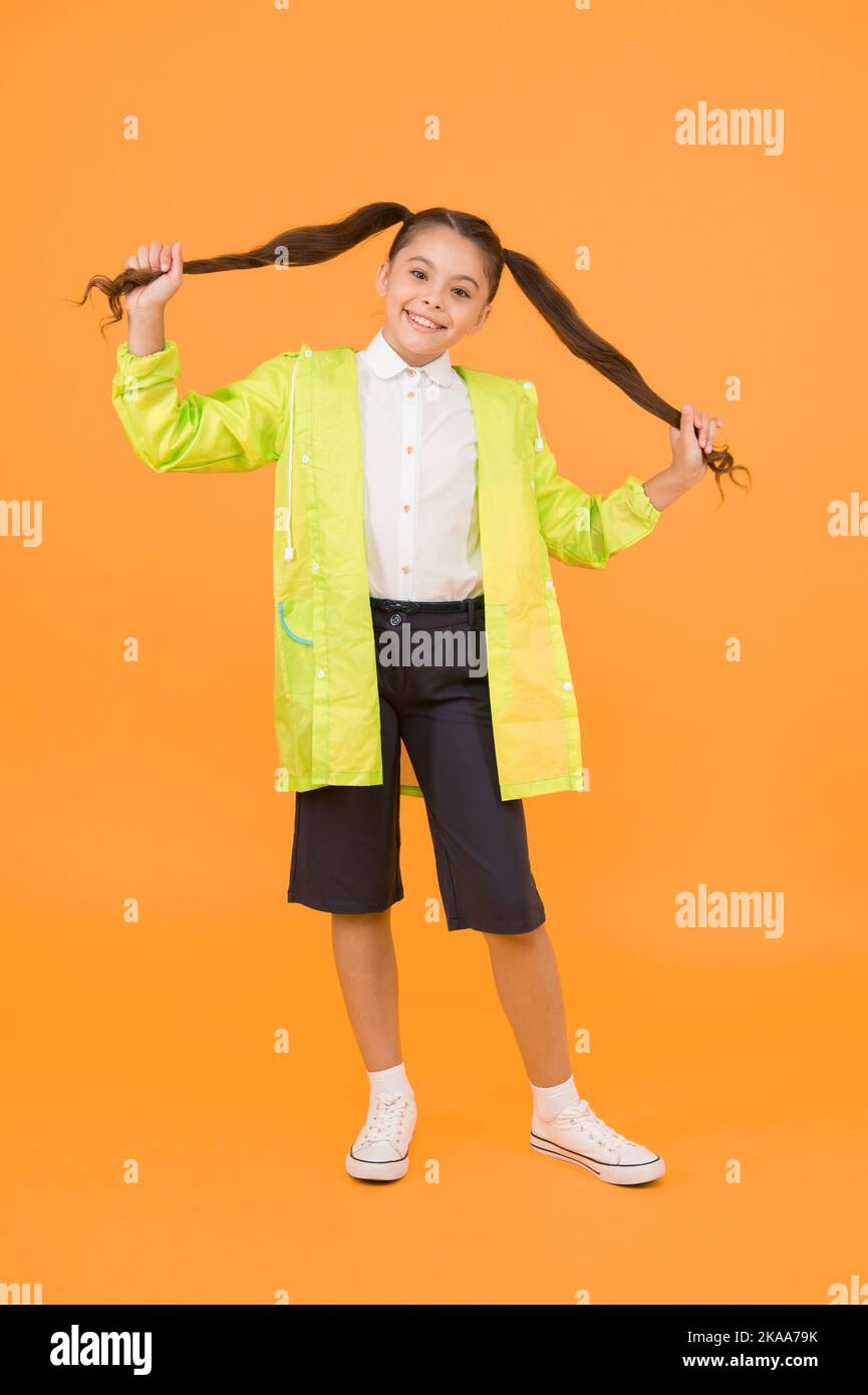 Concept étanche. Adorable enfant. Bonne écolière vêtements de pluie sur fond jaune. Une petite écolière porte des vêtements résistants à l'eau pour les jours de pluie Banque D'Images