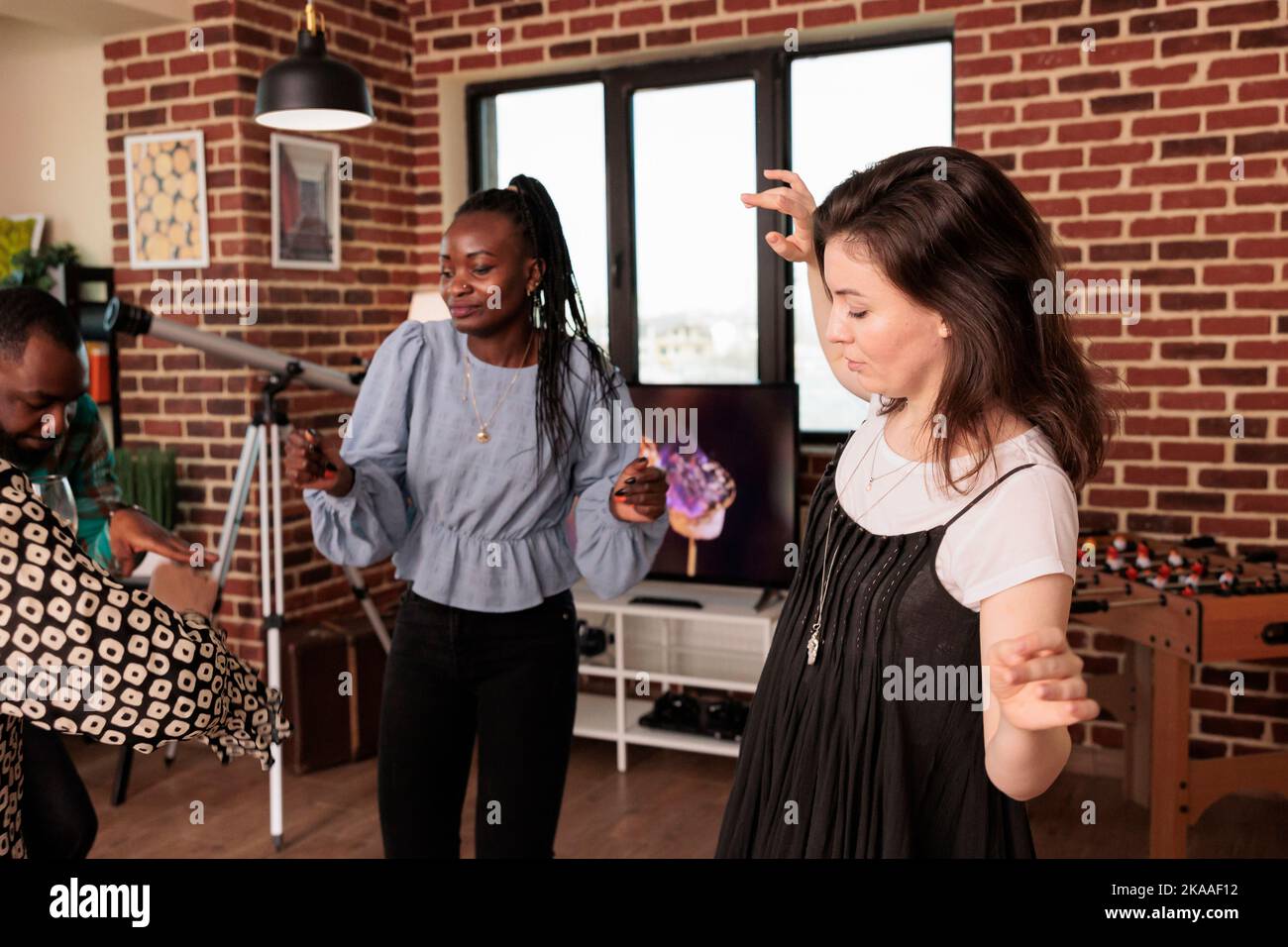 Des femmes culturellement diverses dansent en couple, s'amusent, apprécient la musique chez des amis, des partenaires, des amis à la maison, des réunions faites maison. Des gens multiethniques qui ont du bon temps ensemble. Banque D'Images