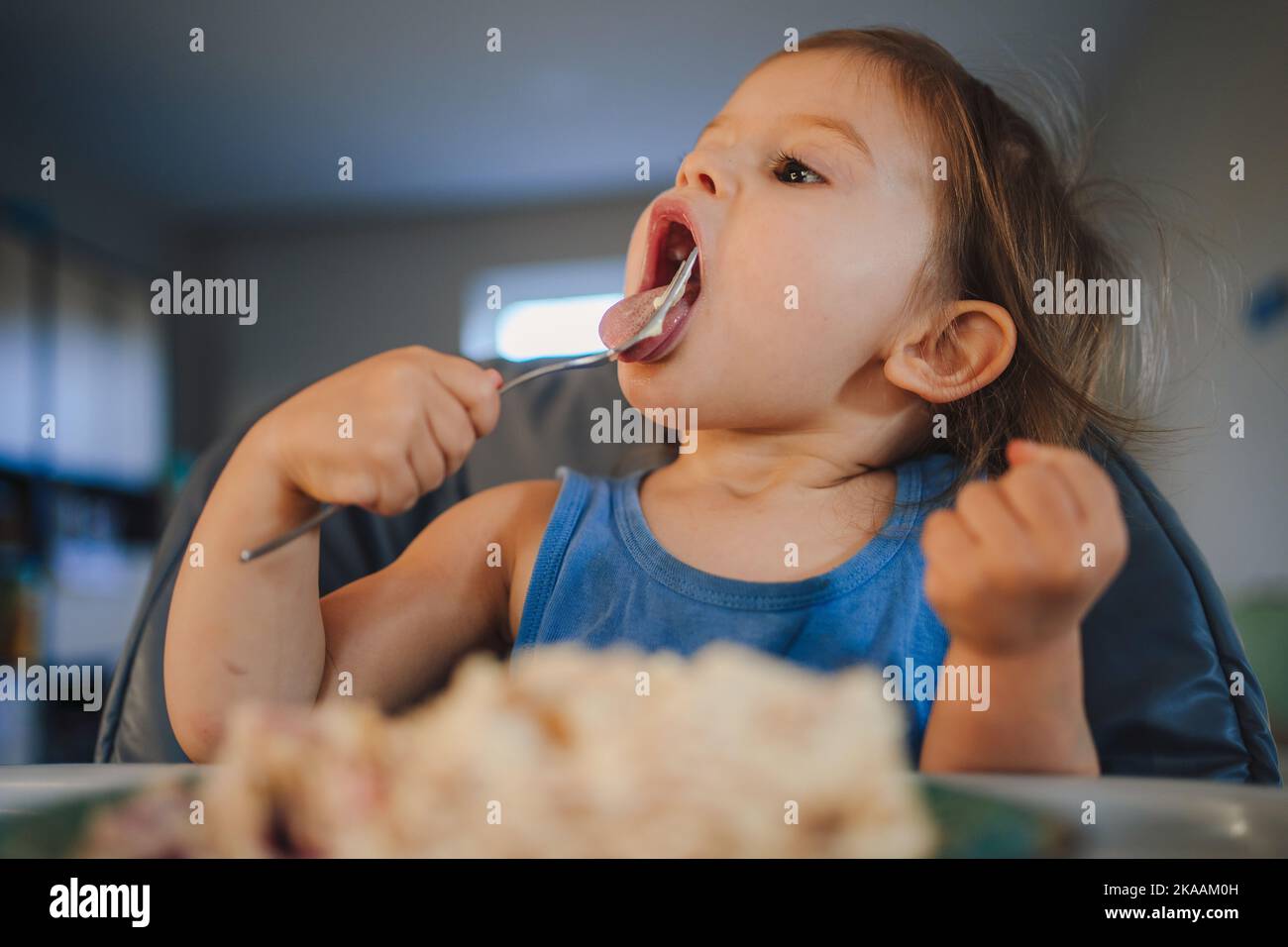 Portrait bébé caucasien fille mangeant de la nourriture de l'assiette à l'aide de la fourchette, assis chaise haute, auto-alimentation. Une alimentation saine pour les enfants. Repas des tout-petits Banque D'Images