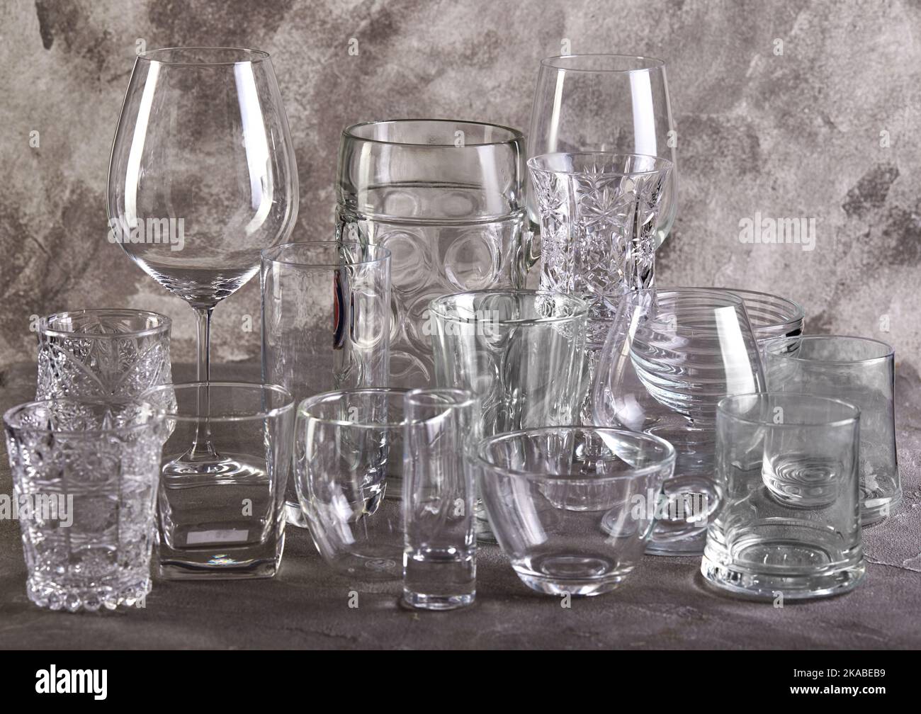 Jeu de verres de différentes tailles et pour différentes boissons sur fond de biton gris Banque D'Images