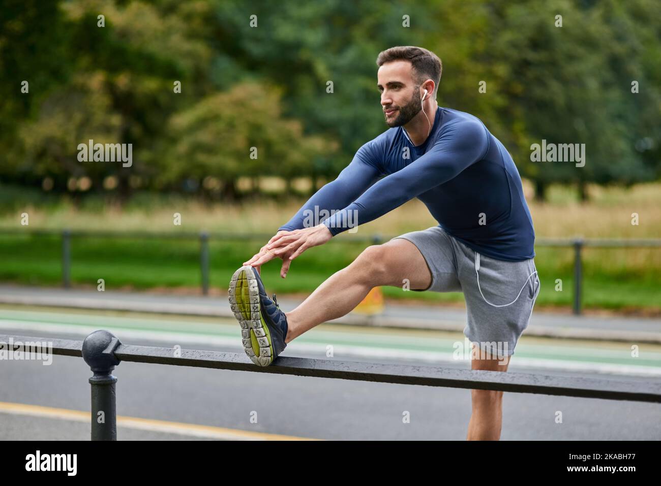 Préparer ses jambes pour une course. Un jeune homme charmant s'échauffe avant son entraînement. Banque D'Images