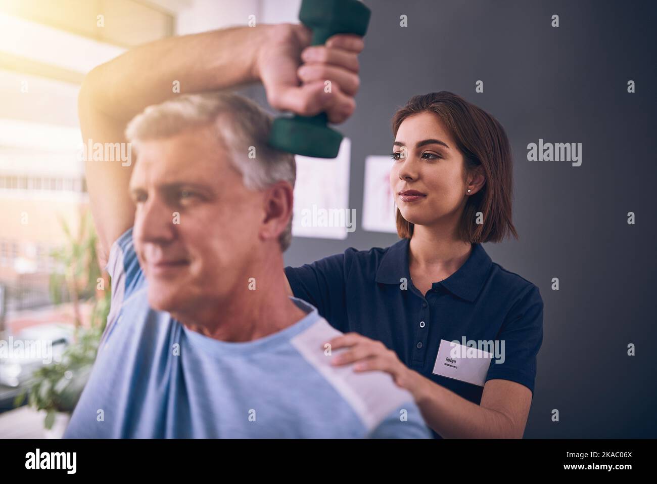 Il est important de rester actif. Une jeune femme physiothérapeute traitant un homme mature. Banque D'Images