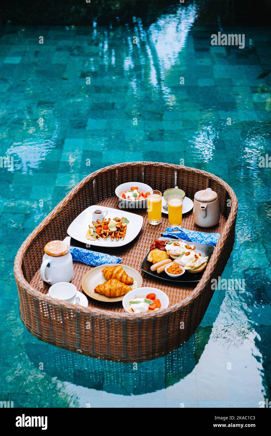 Le plateau de petit-déjeuner en bambou flotte au milieu de la piscine Banque D'Images