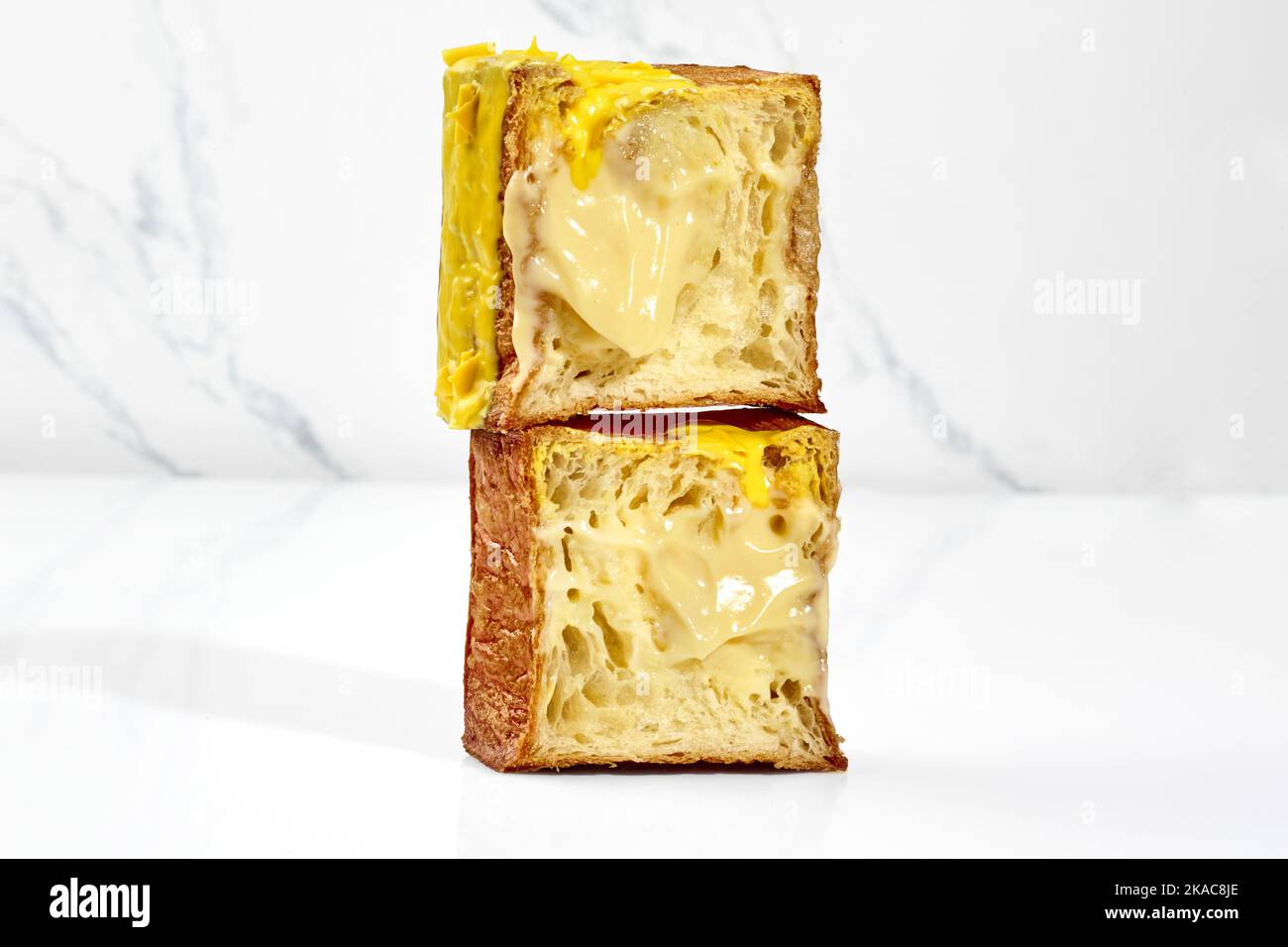 Croissant cubique croustillant avec garniture à la crème vanille, glaçage jaune et copeaux de chocolat Banque D'Images