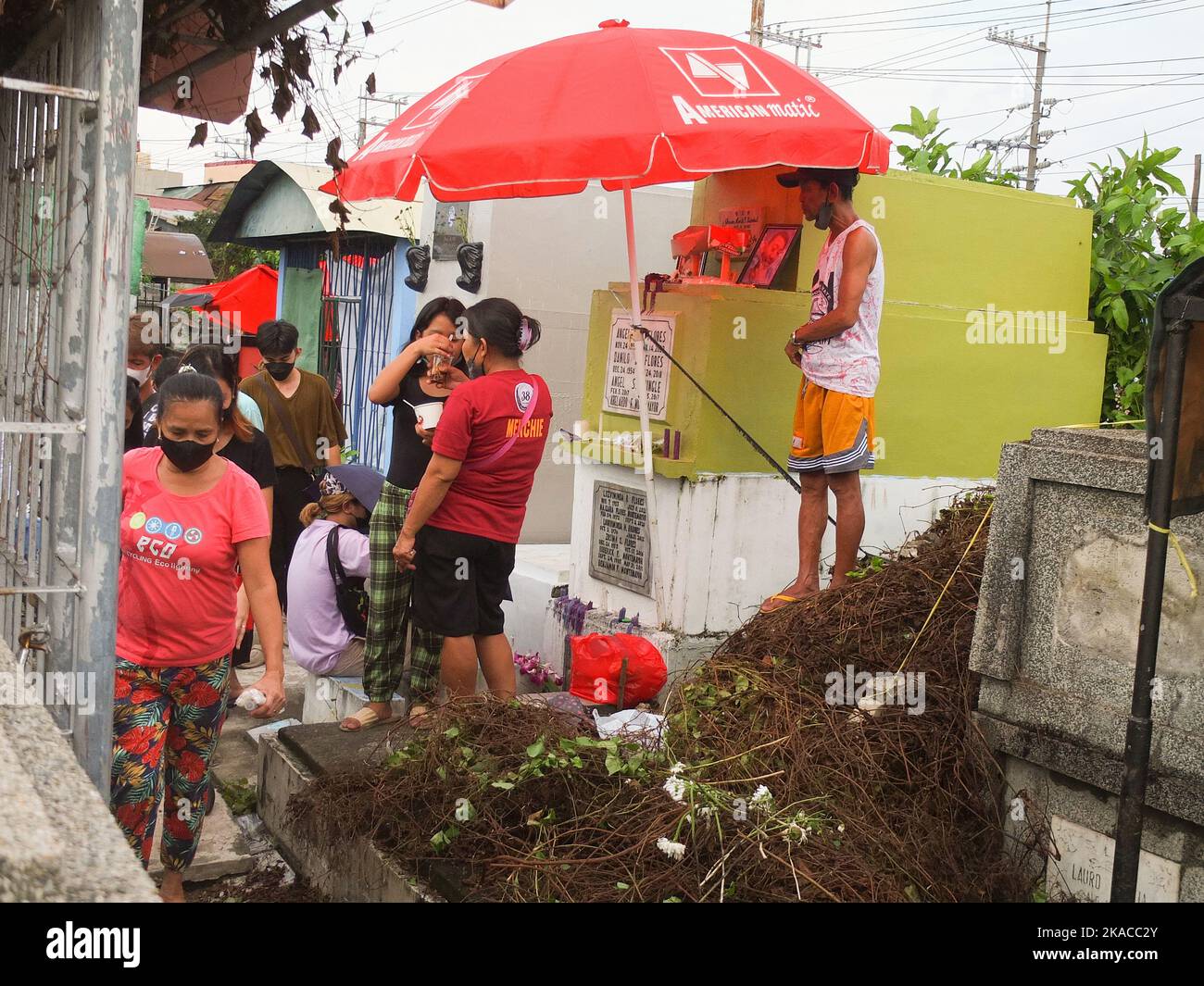 Calooan City, Philippines. 01st novembre 2022. Une famille a installé un  parapluie rouge près de la tombe de son parent décédé pour supporter la  pluie ou la chaleur brûtante du soleil pendant