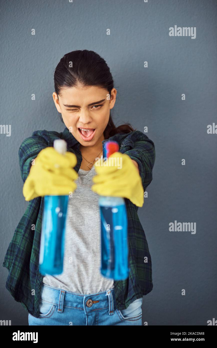 Viser les germes. Portrait en studio d'une jeune femme attirante prenant objectif avec deux flacons de désinfectant. Banque D'Images
