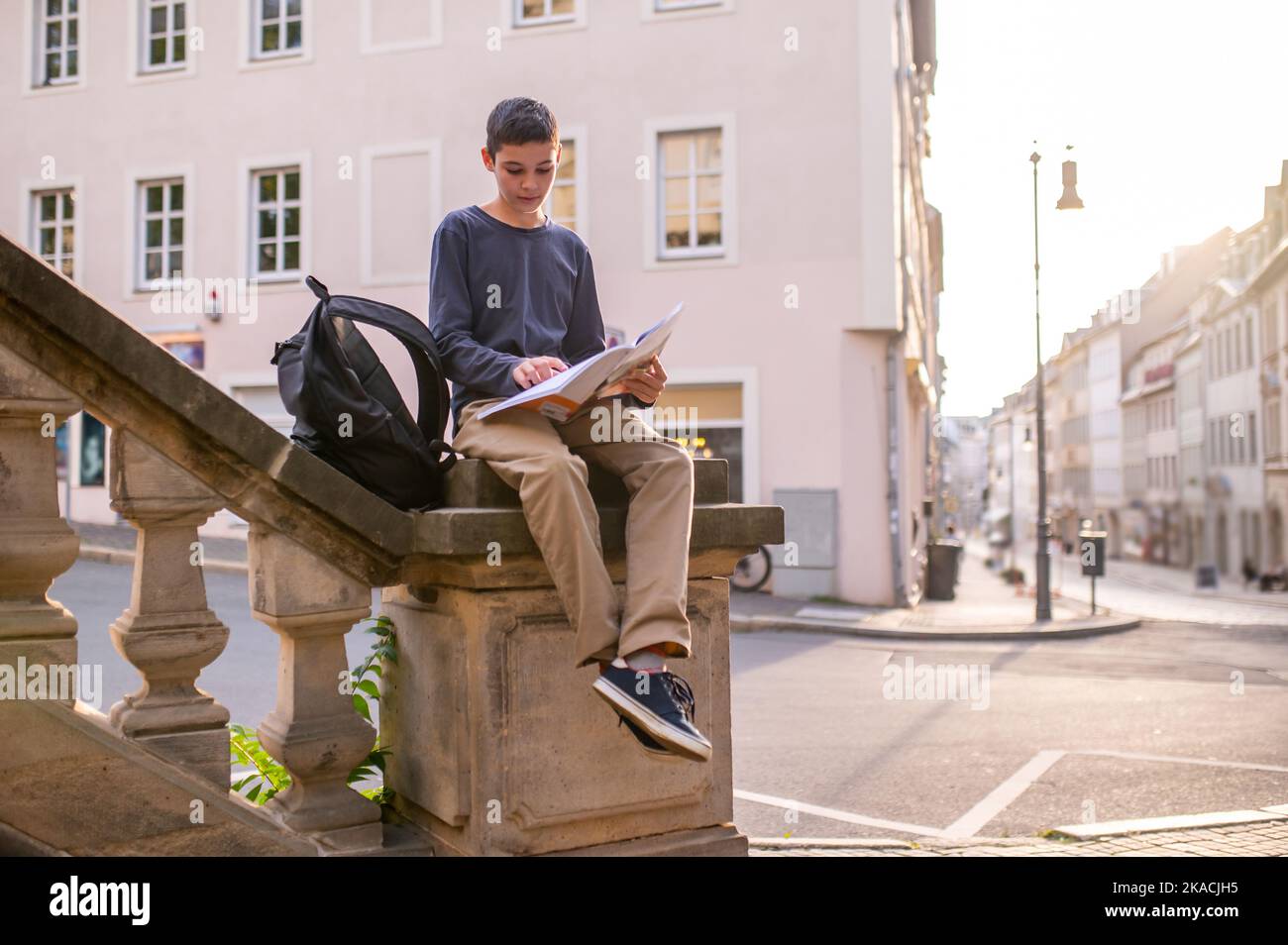 Adolescent concentré avec un livre assis sur la balustrade Banque D'Images