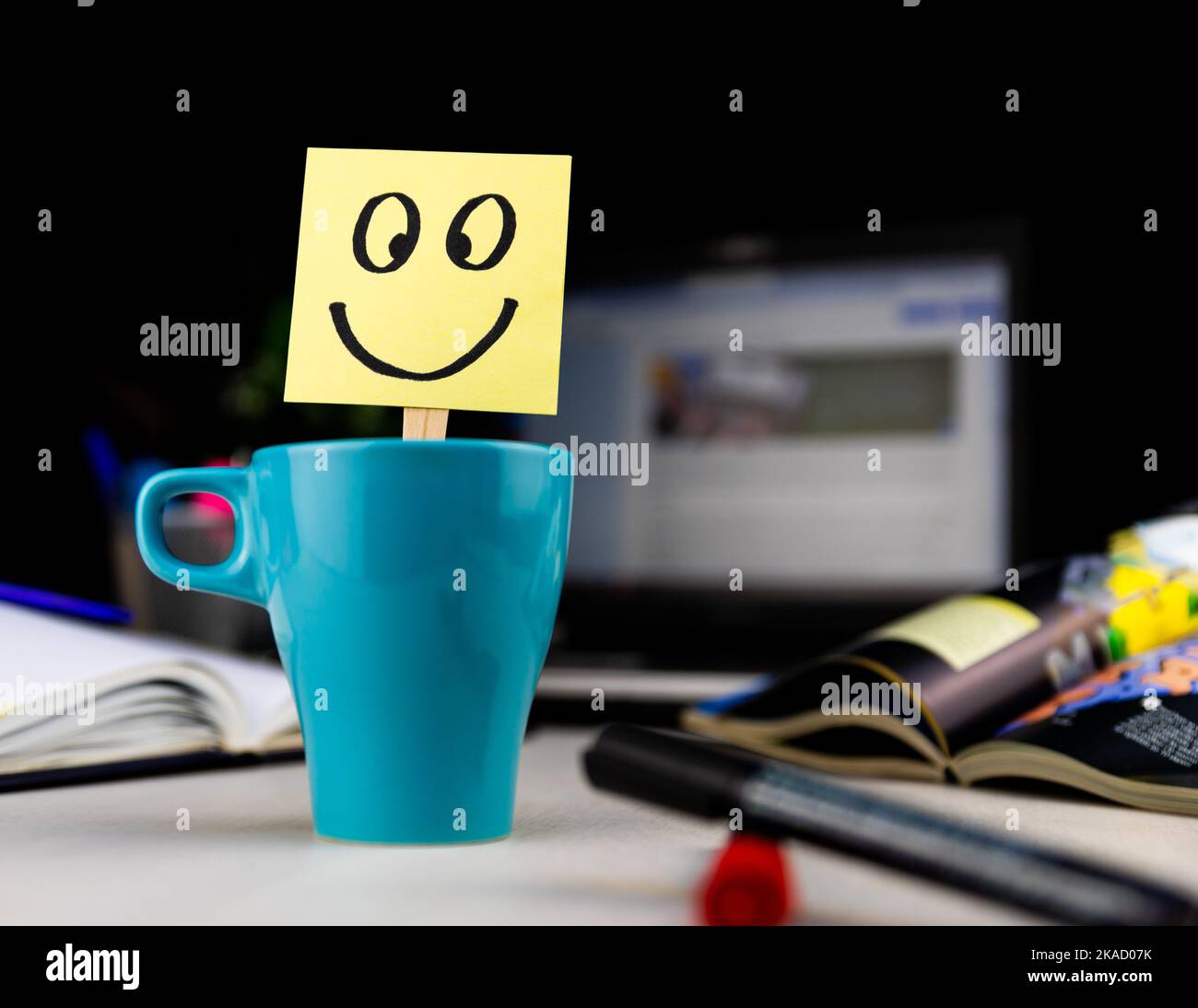 Visage souriant dessiné sur une note collante à l'intérieur d'une tasse de café au bureau. Chaque matin, réveillez-vous avec le sourire Banque D'Images