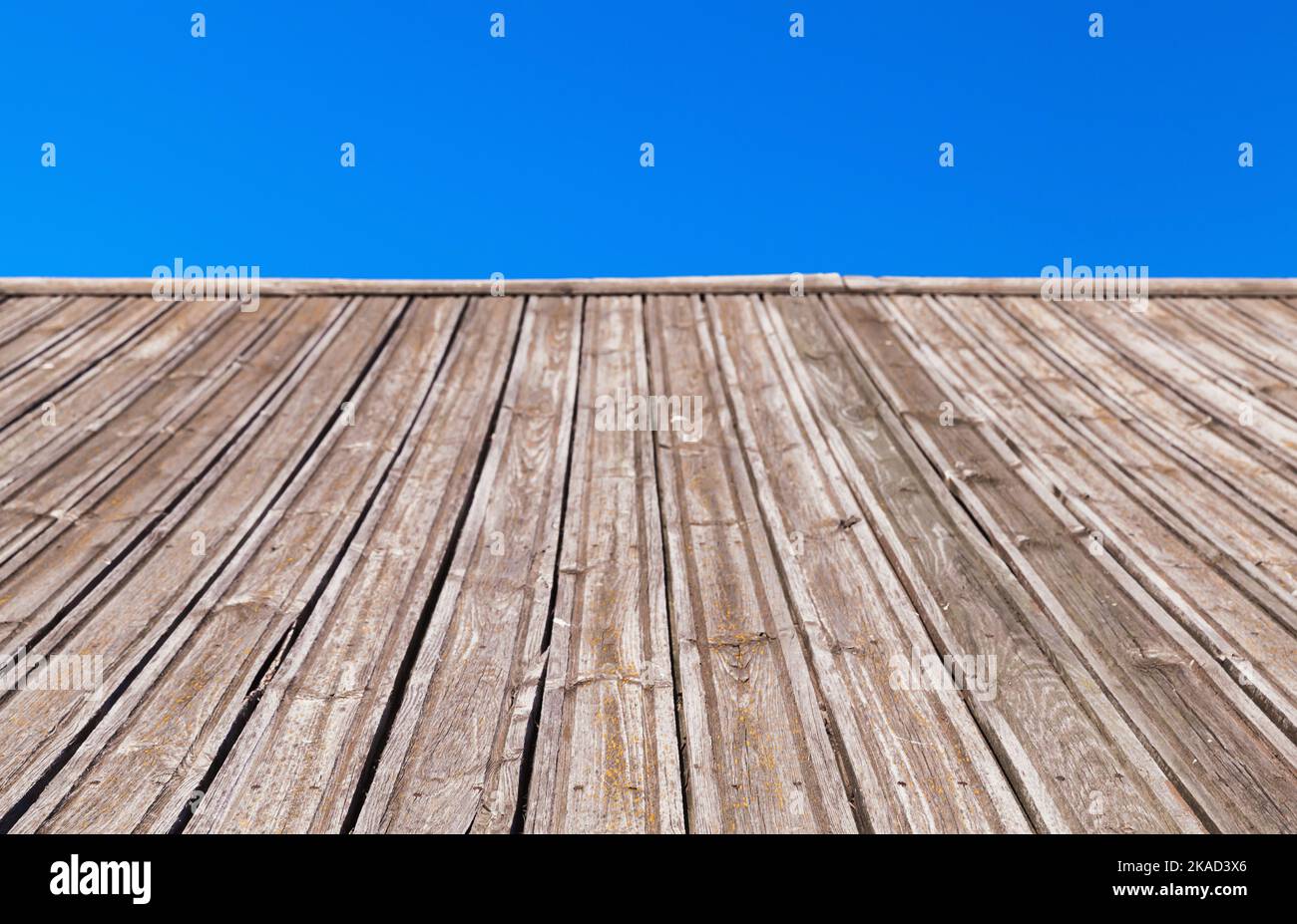 La pente du toit en bois gris est sous un ciel bleu, vue en perspective avec mise au point sélective sur un premier plan Banque D'Images