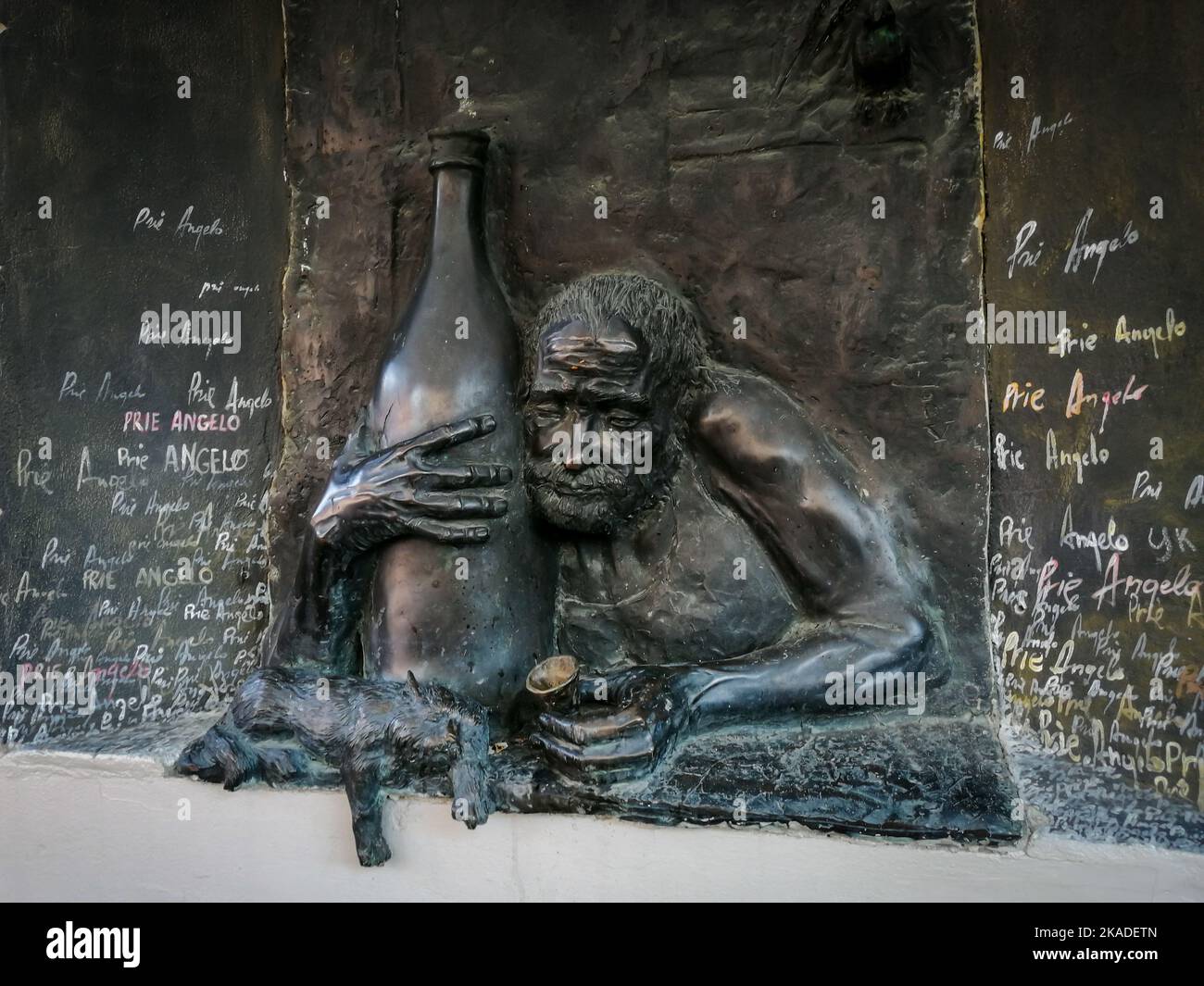 Vilnius, Lituanie - 26 septembre 2022 : Bas-relief en bronze d'un drunkard avec une grande bouteille de vin et un chat. Art sur le mur d'une maison à Uzumis. Banque D'Images