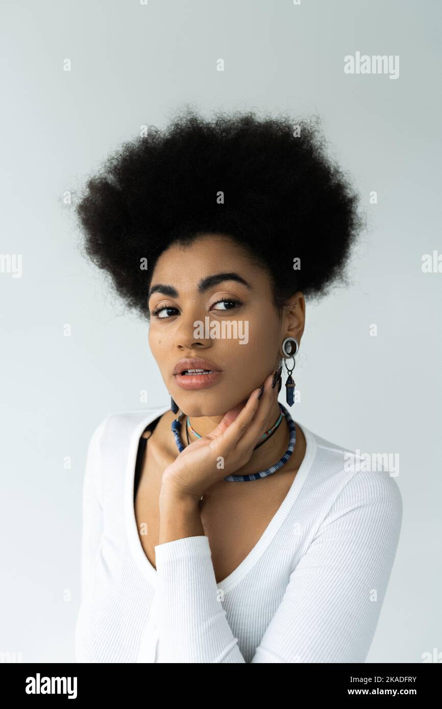jolie femme afro-américaine touchant le visage propre isolé sur blanc, image de stock Banque D'Images