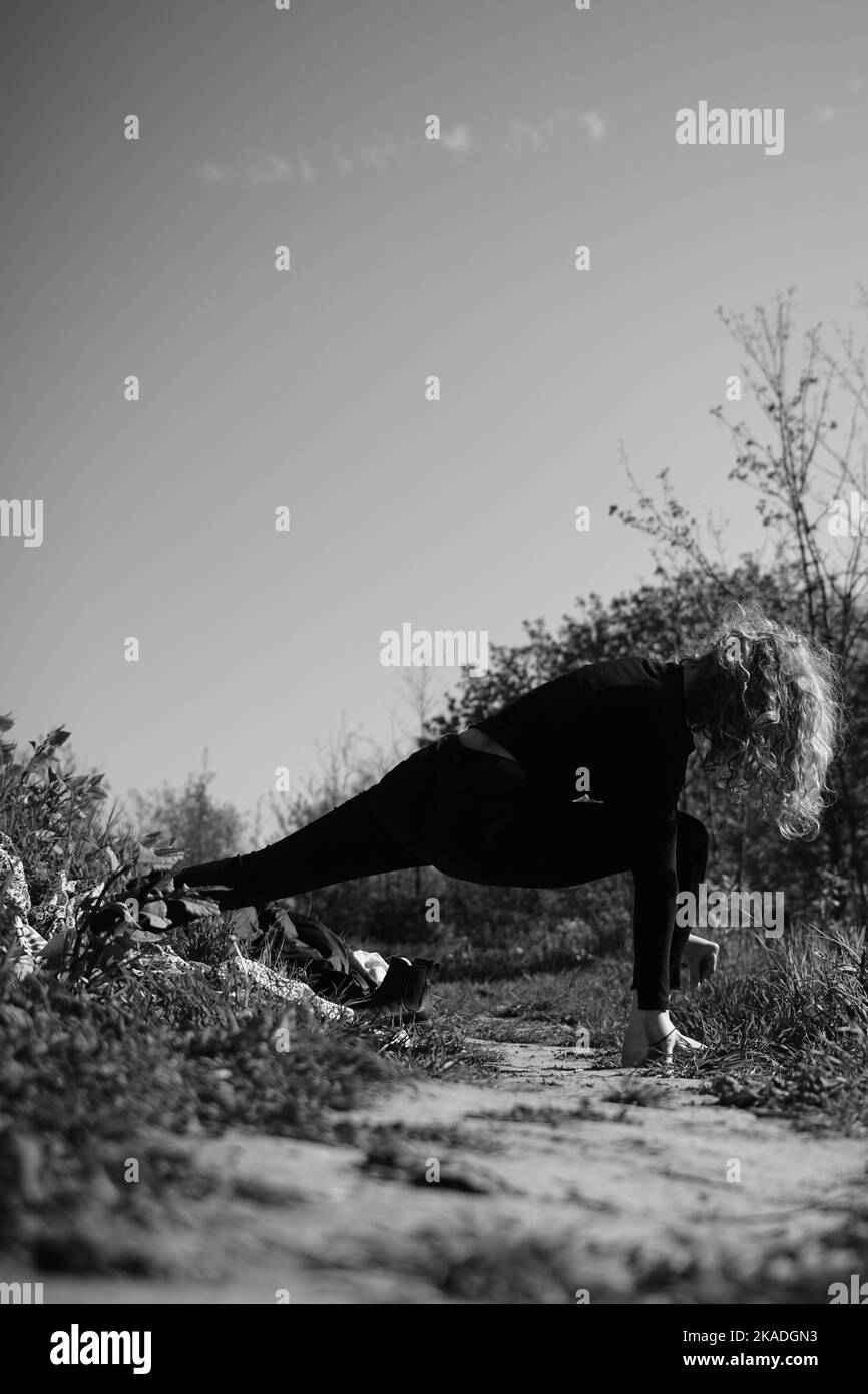 Une échelle de gris d'une femme faisant des exercices dans une forêt par un jour ensoleillé Banque D'Images