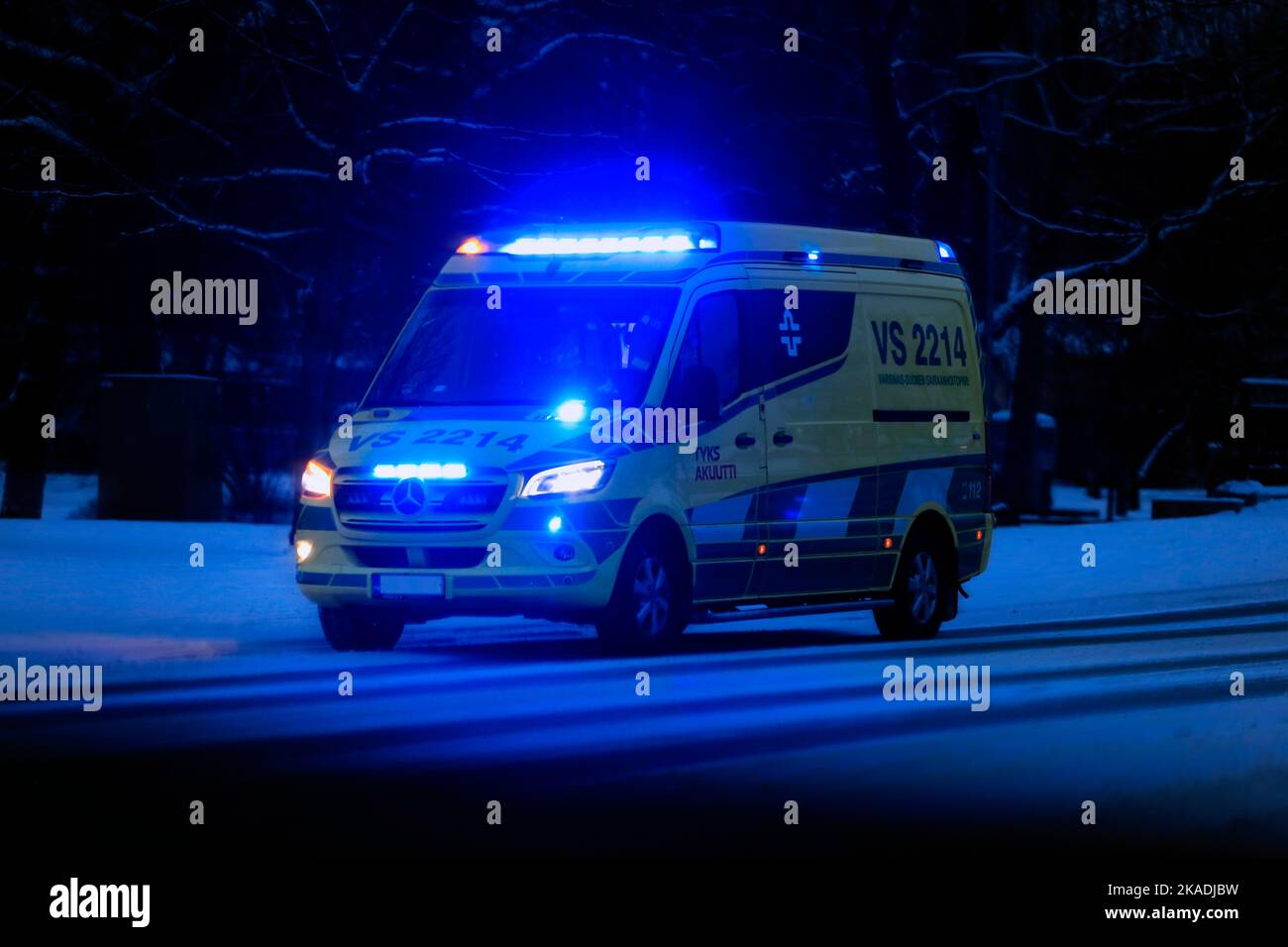 Mercedes-Benz ambulance sur appel dans la rue dans l'obscurité d'une nuit d'hiver avec des lumières bleues clignotantes. Salo, Finlande. 28 décembre 2021. Banque D'Images