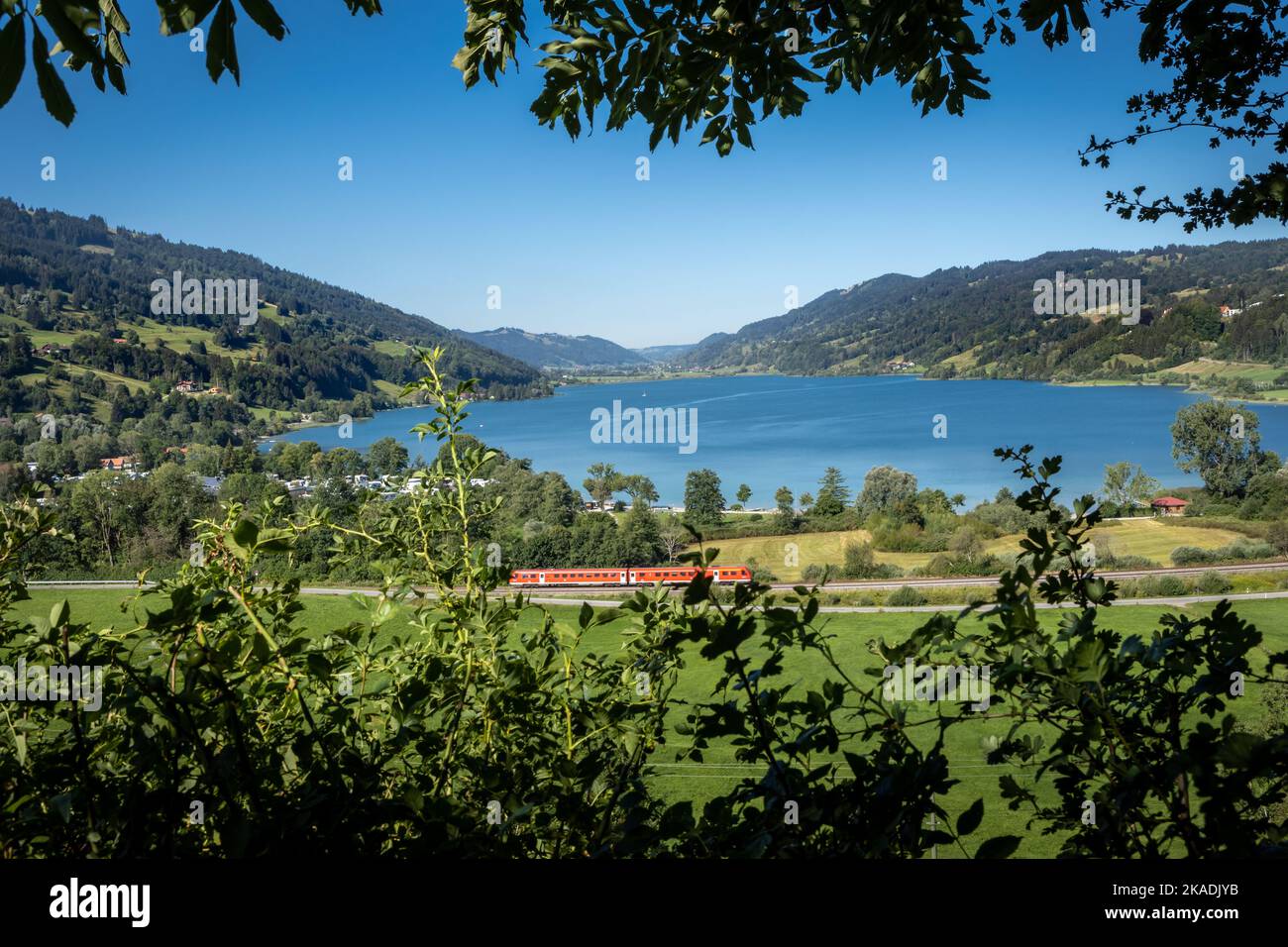 Montagnes et panorama sur le lac de Grosser Alpsee dans les Alpes bavaroises près d'Immenstadt im Allgau, Allemagne. Train rouge en premier plan. Banque D'Images