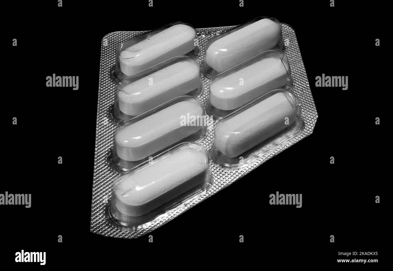 Cliché macro des médicaments génériques de pilules blanches sur fond noir. Industrie pharmaceutique. Banque D'Images