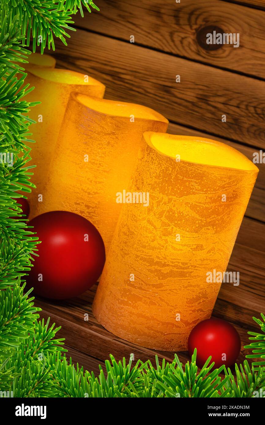 Quatre bougies en cire véritable LED vintage dorées avec branches de sapin et boules de Noël rouges sur fond de bois Banque D'Images