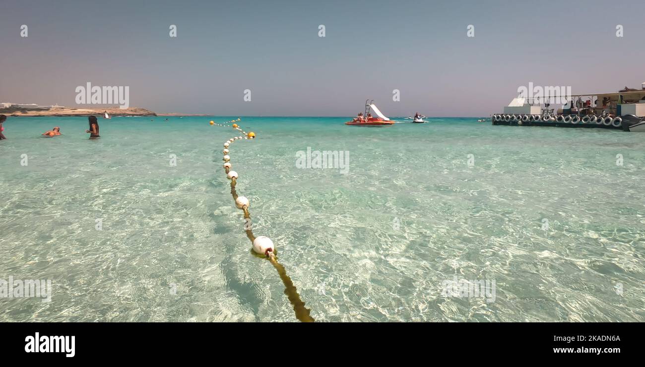 Chaîne de bouées de marqueur flottant dans la mer. Eau turquoise et sable doré à la plage de Nissi, Chypre. Banque D'Images