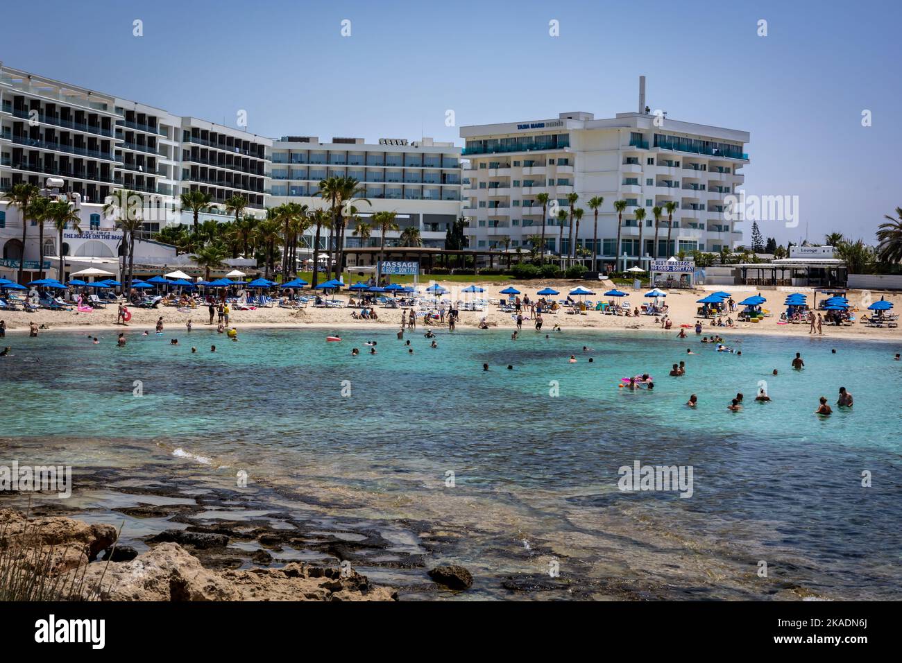 Ayia Napa, Chypre - 24 juin 2022: Plage de Viathia Gonia. Les personnes se baignant dans la mer, les bâtiments de l'hôtel en arrière-plan. Banque D'Images