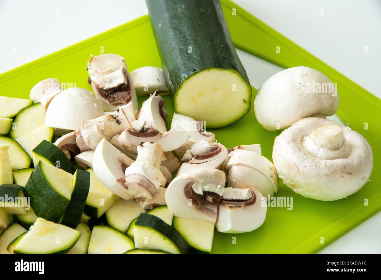Une belle photo de courgettes hachées, et de champignons sur une planche de cuisine verte Banque D'Images