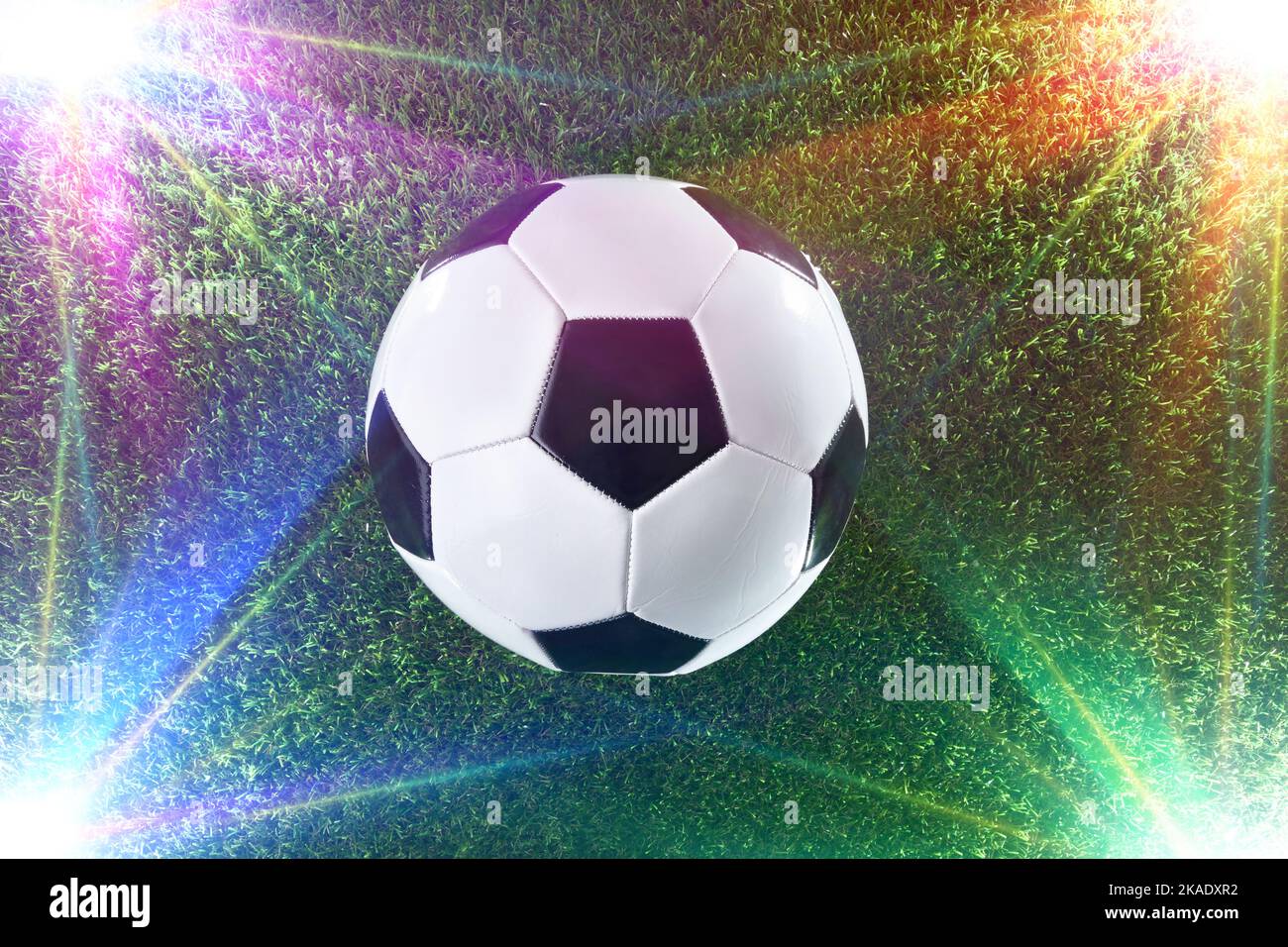 Ballon de football classique sur l'herbe avec des spots de couleur illuminant des coins. Vue de dessus. Banque D'Images