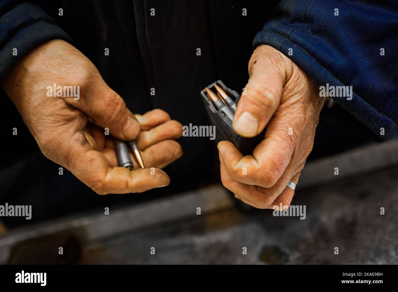 Le travailleur dépose des balles dans un magazine d'armes à feu Banque D'Images