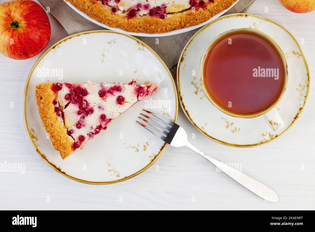 Morceau de tarte aux pommes et aux groseilles maison et une tasse de thé sur une table en bois blanc. Vue de dessus. Banque D'Images Morceau de tarte aux pommes et aux groseilles maison et une tasse de thé sur une table en bois blanc. Vue de dessus. Banque D'Images