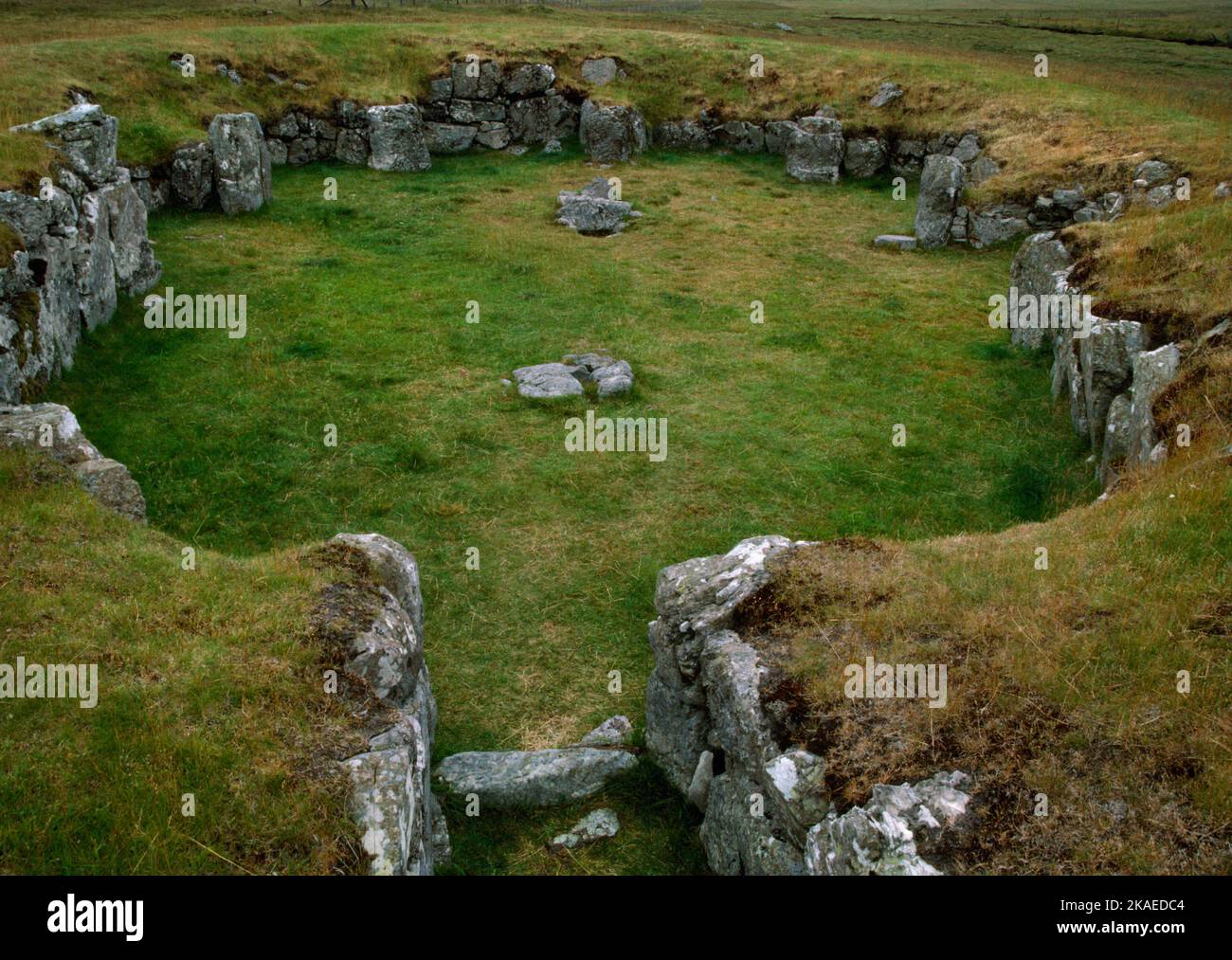 Vue W de l'intérieur du « temple » néolithique de Stanydale, Shetland, Écosse, Royaume-Uni, montrant le passage d'entrée, deux postholes bordées de pierre et 6 alcôves. Banque D'Images