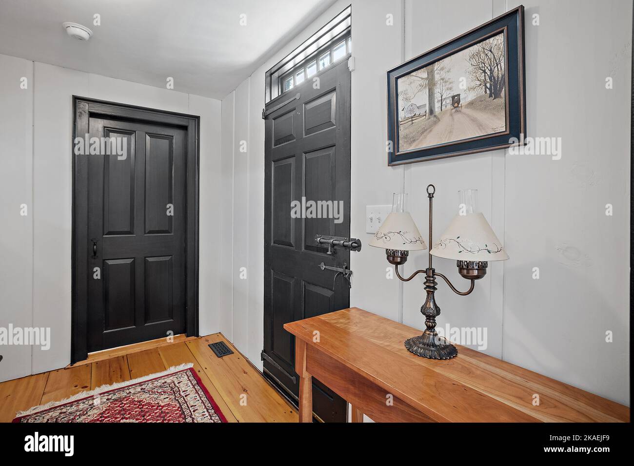 L'intérieur d'un couloir avec porte avant noire et une lampe de table de  style ancien sur une table en bois Photo Stock - Alamy