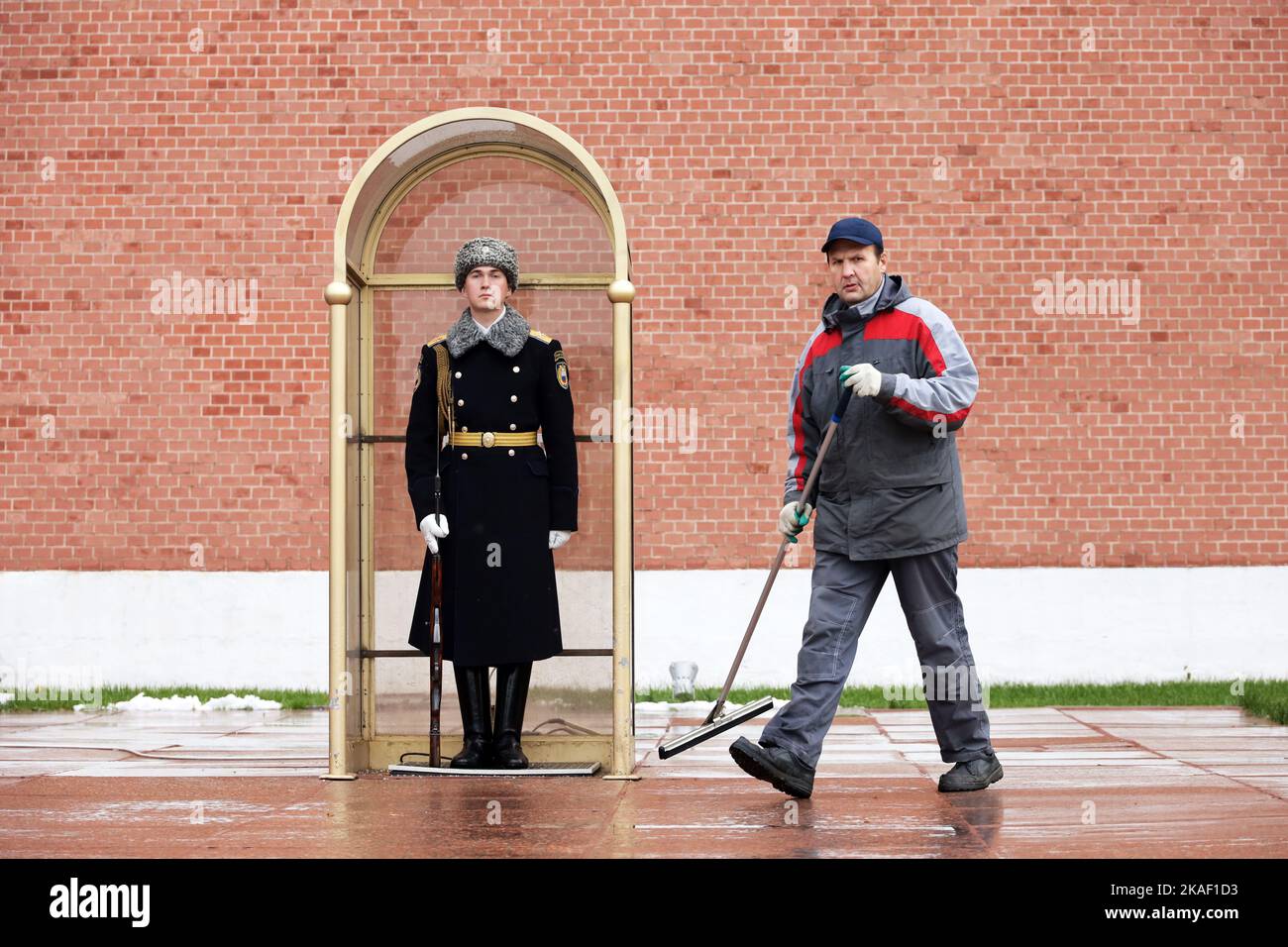 Le concierge nettoie la rue près du soldat russe de garde d'honneur près du mur du Kremlin Banque D'Images