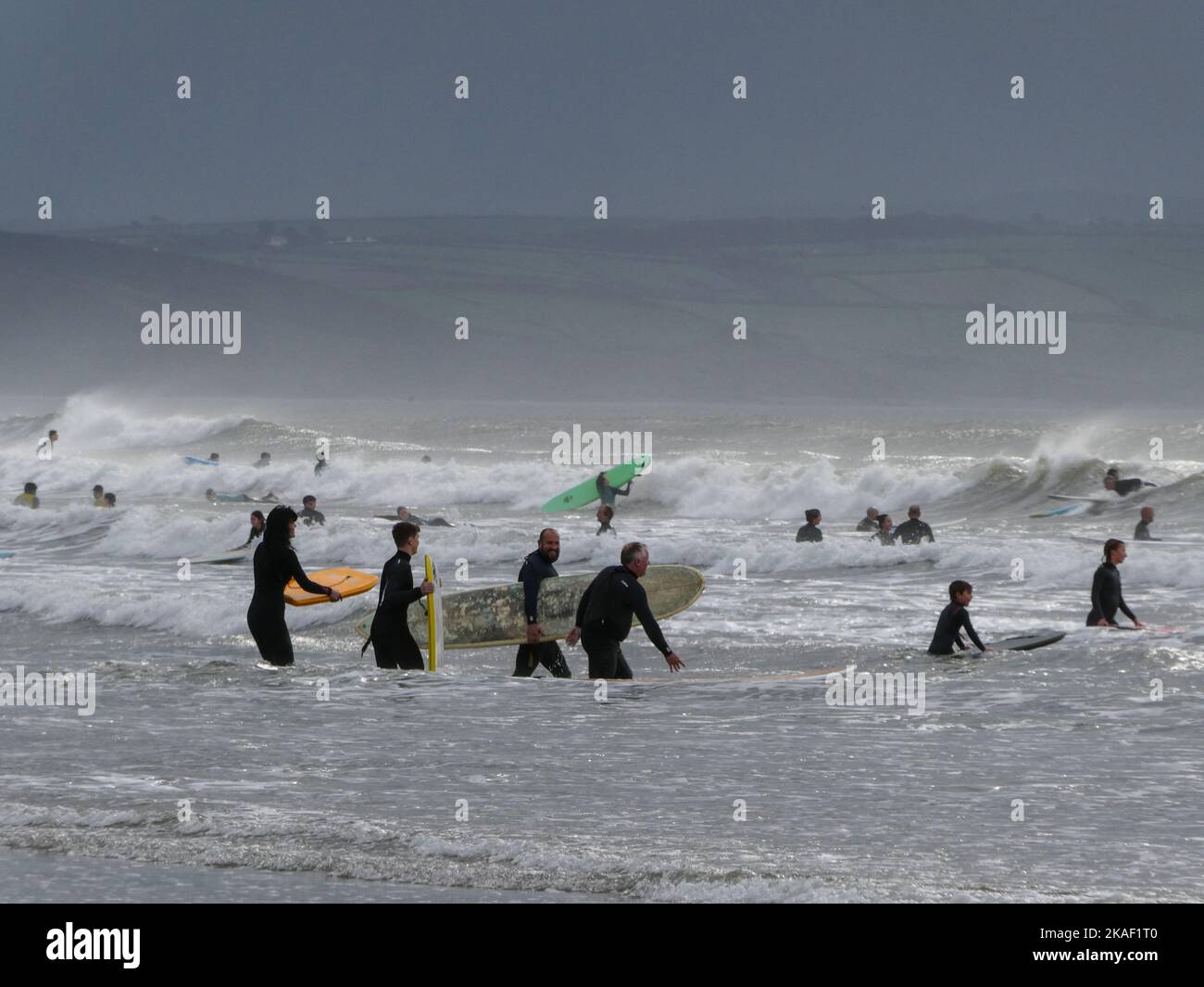 Les surfeurs pénètrent dans la mer dans des conditions difficiles lors d'une journée venteuse à Saunton Sands, dans le Devon, en Angleterre Banque D'Images