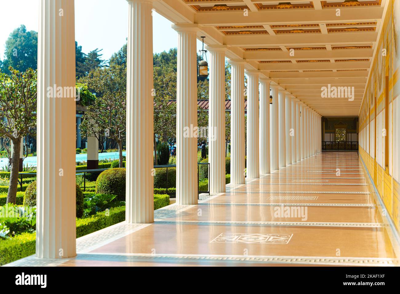 Le luxueux couloir du musée J. Paul Getty villa avec des colonnes blanches et un jardin avec des arbres verts Banque D'Images