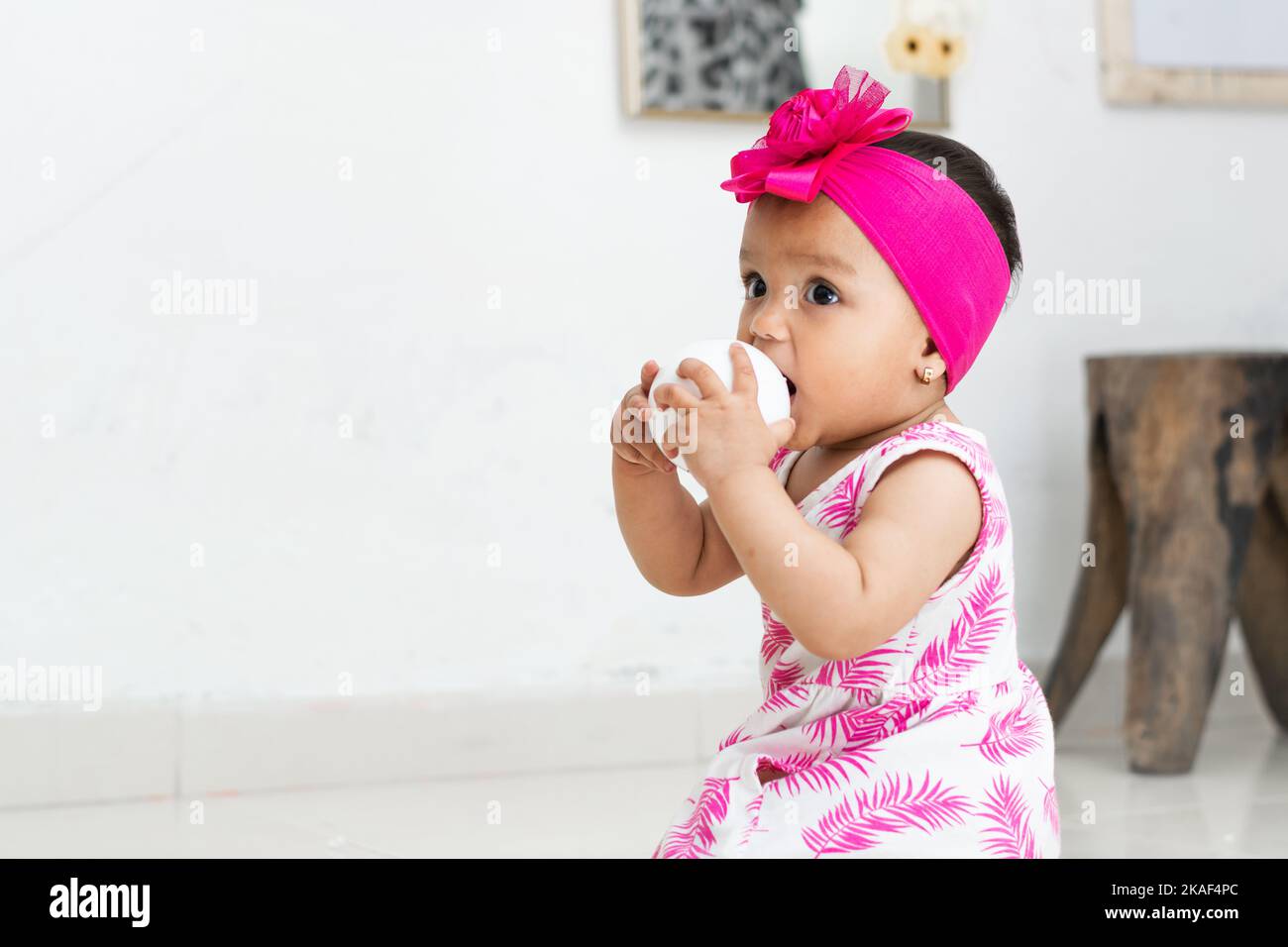 magnifique bébé brunette, assis sur le sol jouant avec une balle. fond blanc dans le salon d'une maison colombienne. Banque D'Images