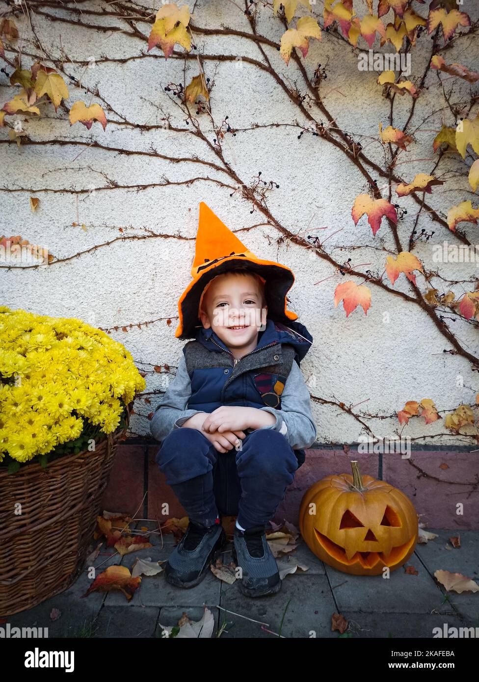 Joyeux garçon pendant les fêtes d'Halloween portant un chapeau de citrouille orange avec une citrouille en forme de citrouille Banque D'Images