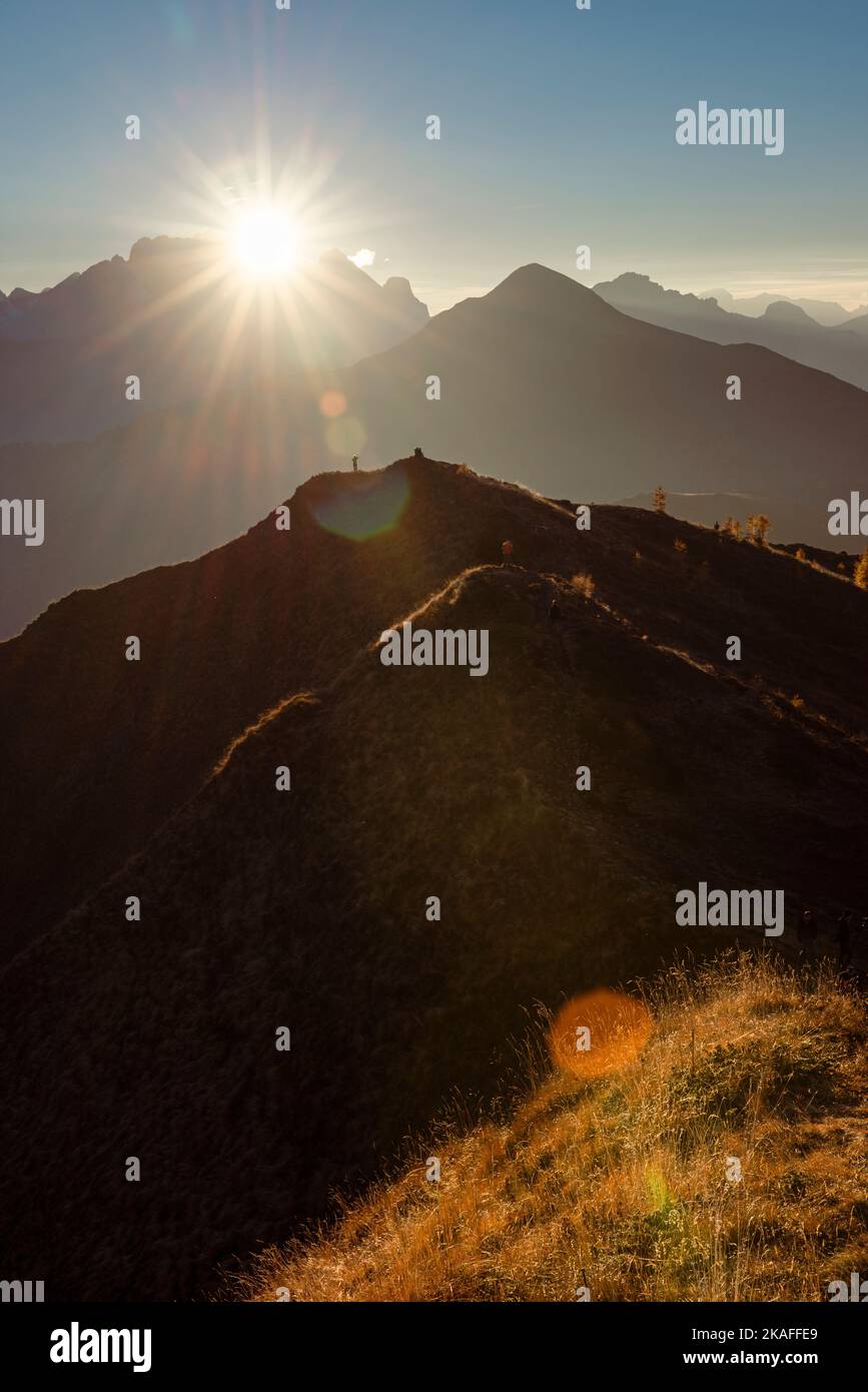 Randonneurs sur un pic panoramique à Passo di Giau dans le chaud contre-jour du coucher du soleil sur le sommet de la Marmolada, Dolomites, Italie Banque D'Images