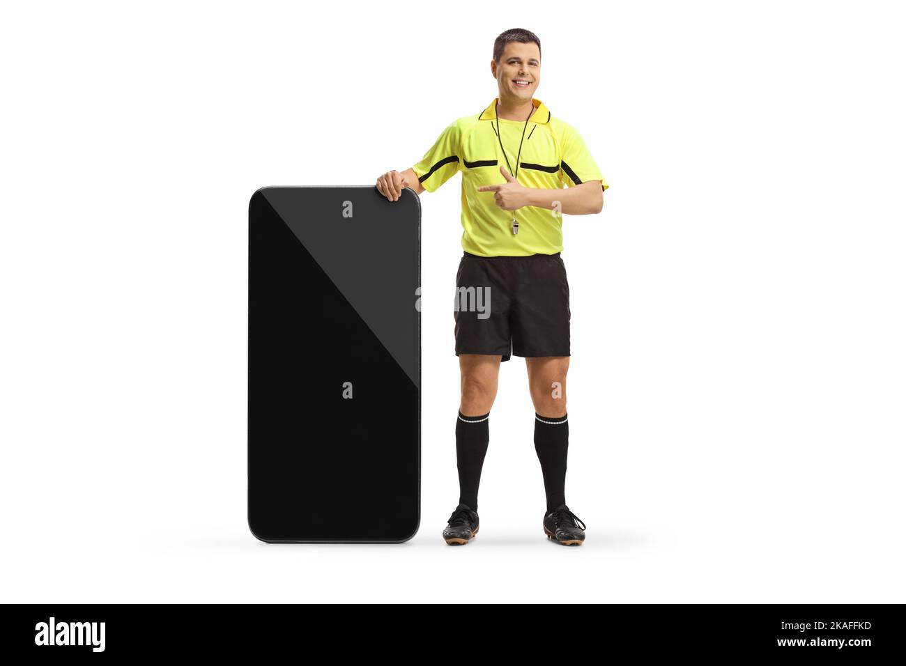 Portrait complet d'un arbitre de football debout à côté d'un grand téléphone portable et pointant isolé sur fond blanc Banque D'Images