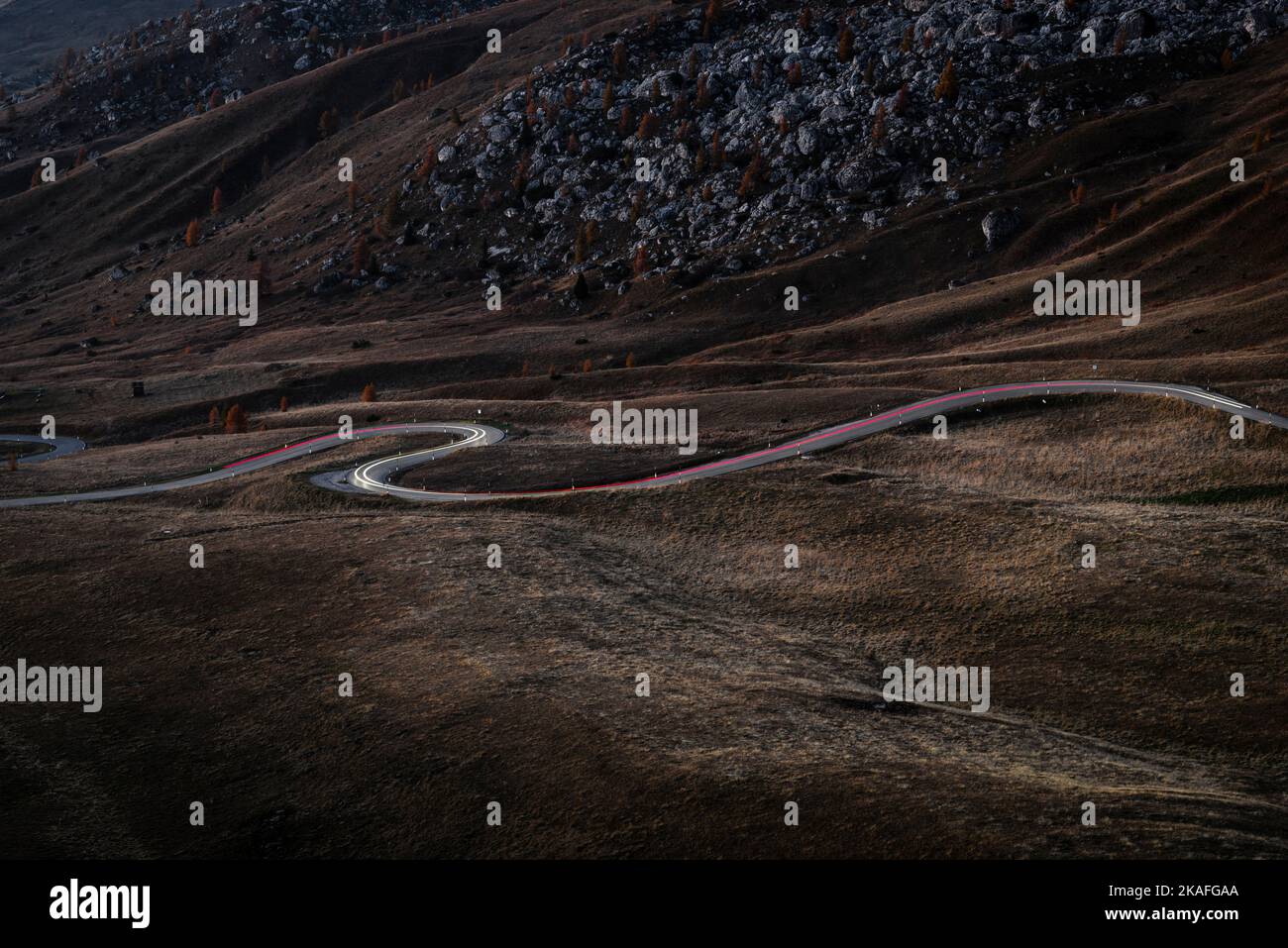 Traces de lumières des voitures roulant sur la route sinueuse à travers les montagnes automnales à Passo di Giau au crépuscule, Dolomites, Italie Banque D'Images