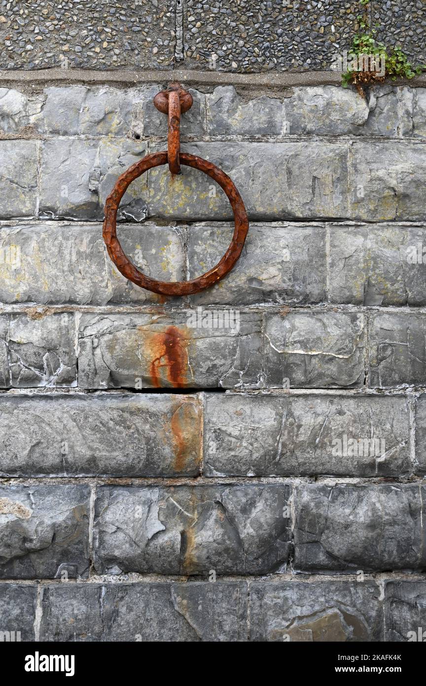 Ancien anneau d'amarrage en métal rouillé sur un vieux mur. Chaîne en métal rouillé sur le grès. Banque D'Images