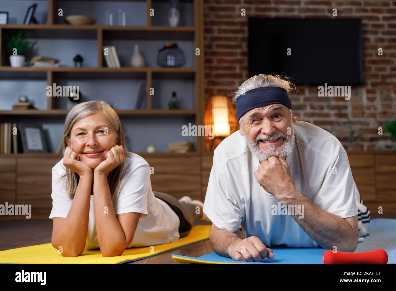 Heureux à cheveux gris mature couple âgé faisant de la gymnastique ensemble à la maison. Un mode de vie actif et sain pour les retraités. Fitness, loisirs, bien Banque D'Images
