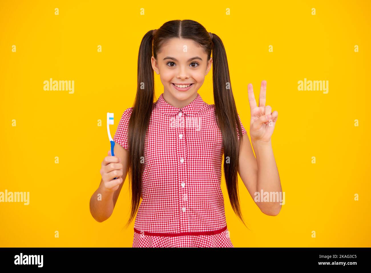 Portrait de la jeune fille caucasienne tient une brosse à dents se brossant ses dents, routine du matin, hygiène dentaire, isolé sur fond jaune. Joyeux adolescent Banque D'Images