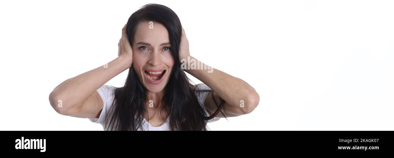 Jeune femme brune couvrant les oreilles avec les mains, les yeux ouverts, criant Banque D'Images