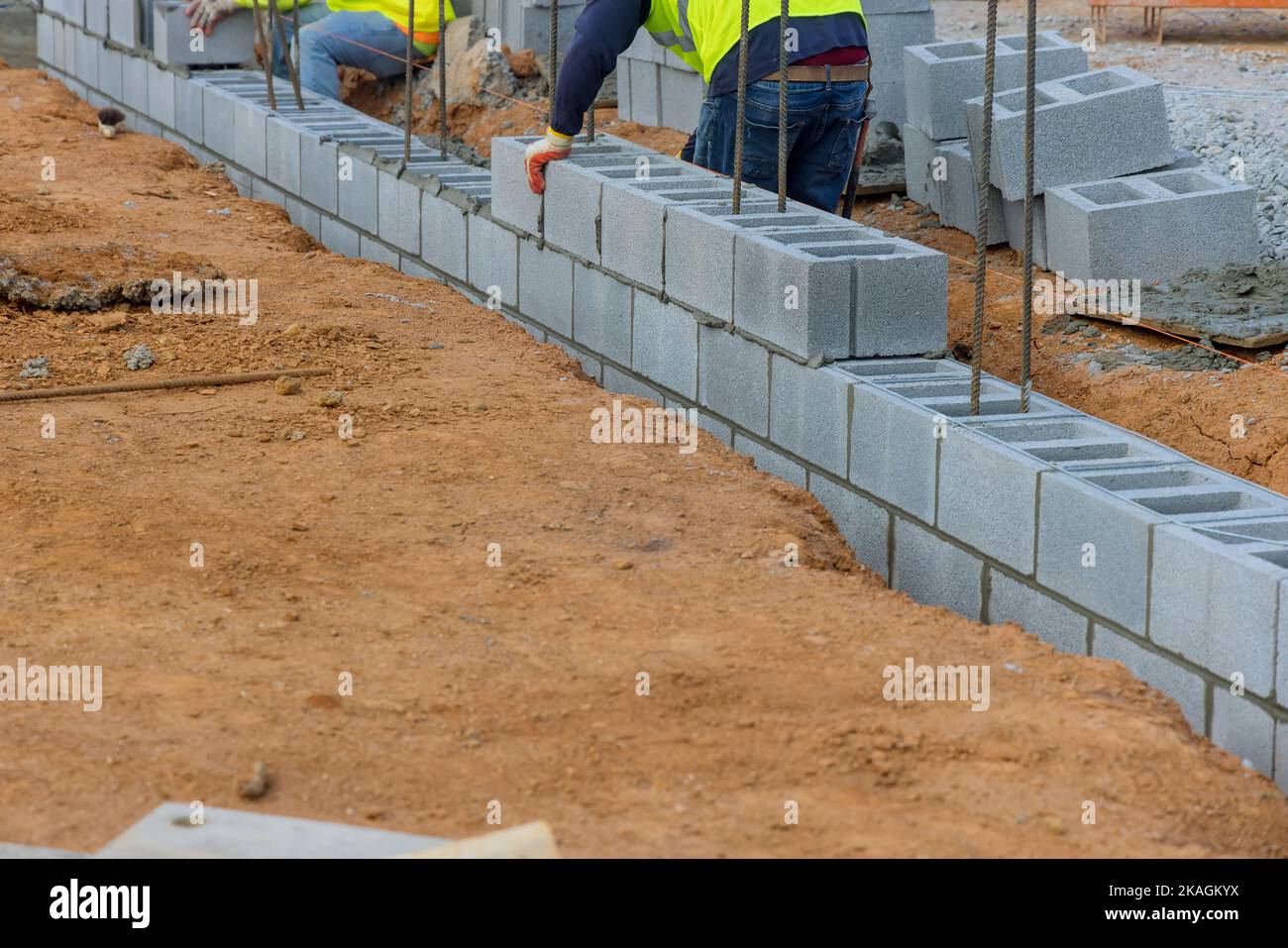 Un employé de la société de construction de briques mettant en place une autre rangée de blocs de ciment sur le sol Banque D'Images