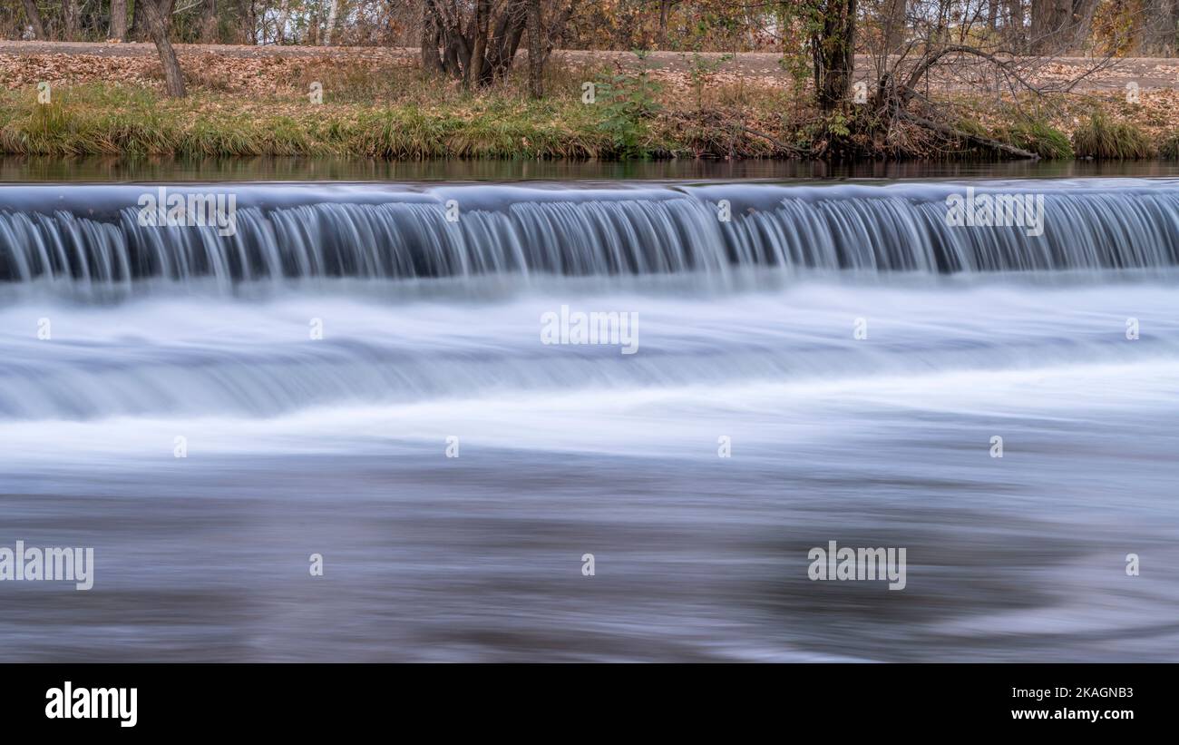 Eau en cascade au-dessus d'un barrage de dérivation sur la rivière poudre avec décor d'automne, nature et concept d'industrie Banque D'Images