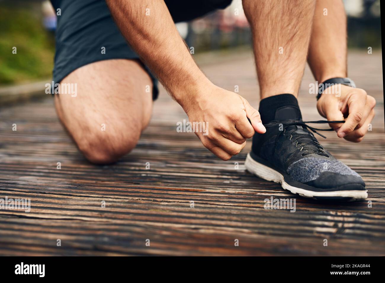 Mieux vaut faire un double nœud. Gros plan d'un jeune sportif qui noue ses lacets tout en faisant de l'exercice à l'extérieur. Banque D'Images