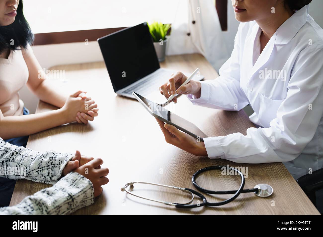 Portrait d'un médecin conseillant des clients sur des problèmes de santé tenant une tablette pour travailler et parlant aux patients qui viennent à un traitement Banque D'Images